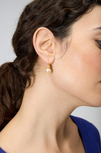 Close-up of a woman's ear wearing Gold Plated Pearl Drop Earrings; her dark hair is tied back, and she is in a blue top.