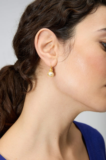 Close-up of a woman's ear wearing Gold Plated Pearl Drop Earrings; her dark hair is tied back, and she is in a blue top.