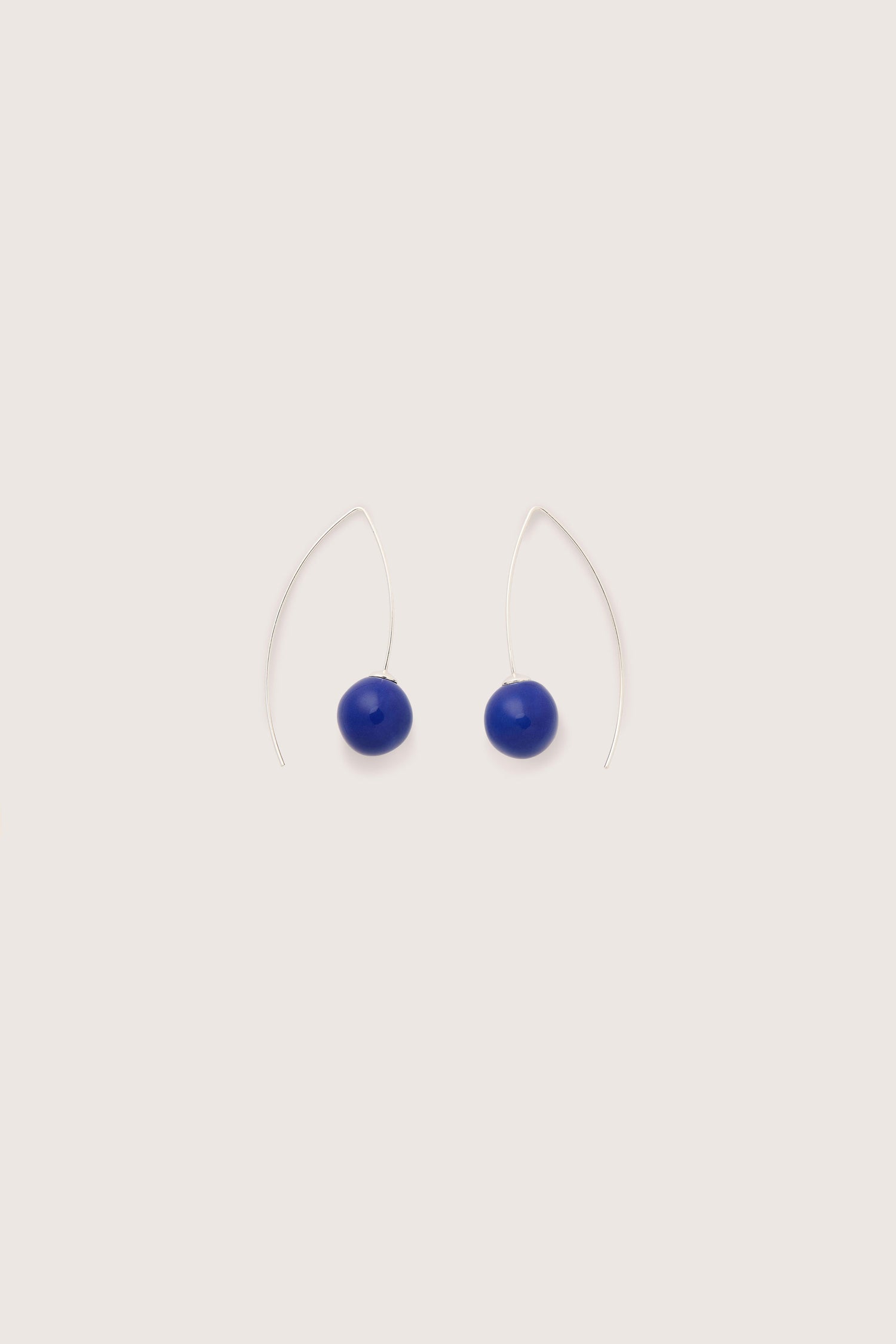 The Handmade Ceramic Bead Earrings are a pair of minimalist silver wire earrings featuring blue oval beads, showcasing artisanal craftsmanship. Fashioned from 925 sterling silver, these handmade ceramic bead earrings bring a touch of elegance to any ensemble.