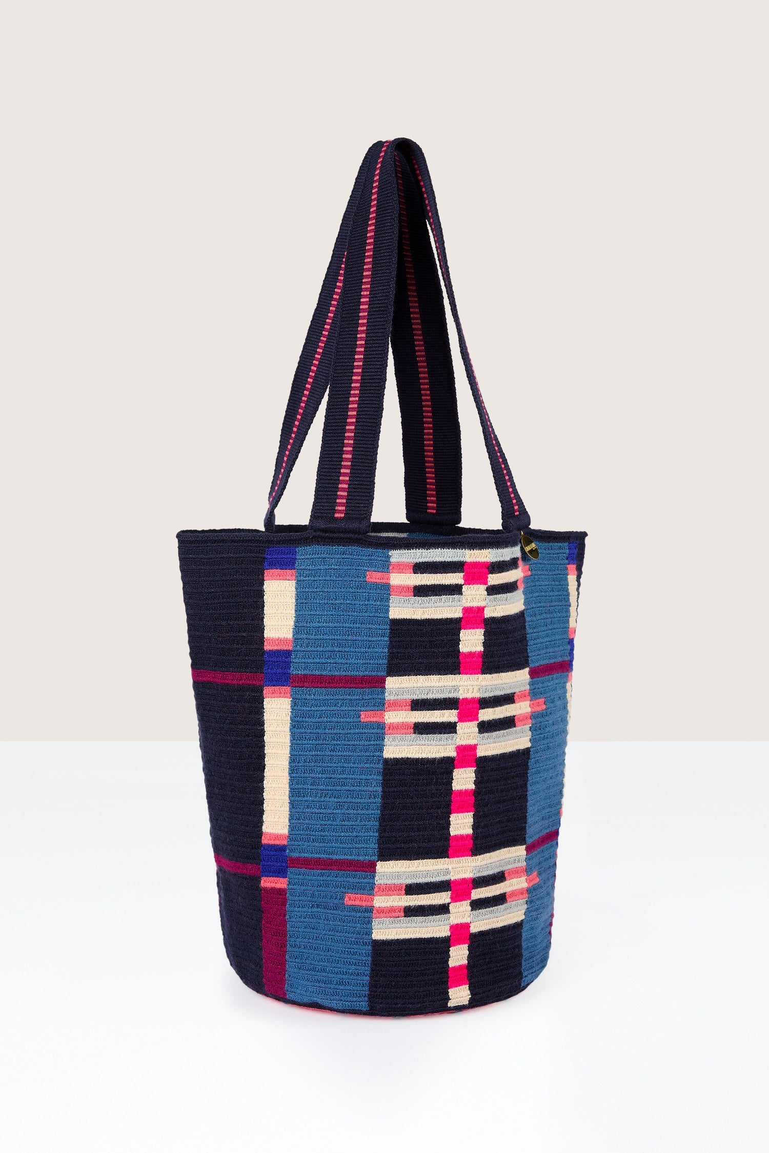 A Handcrafted Cala Tote Bag featuring blue and multicolored geometric patterns, with two handles, set against a neutral background.