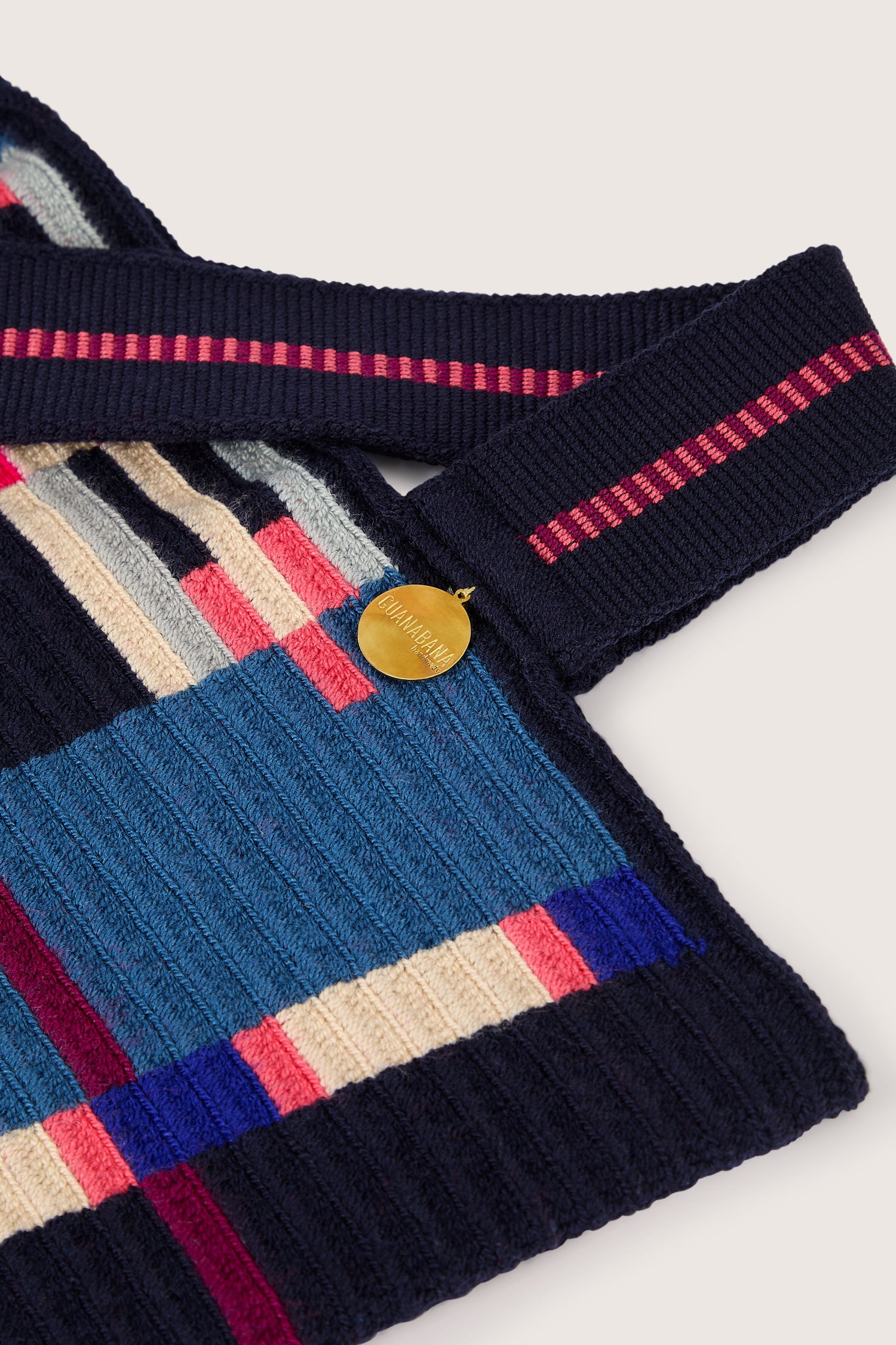 Close-up of the Handcrafted Cala Tote Bag, showcasing a geometric pattern in blue, pink, and cream stripes. It features a labeled gold circular tag and a dark strap with pink stripes, all meticulously crafted by skilled artisans.