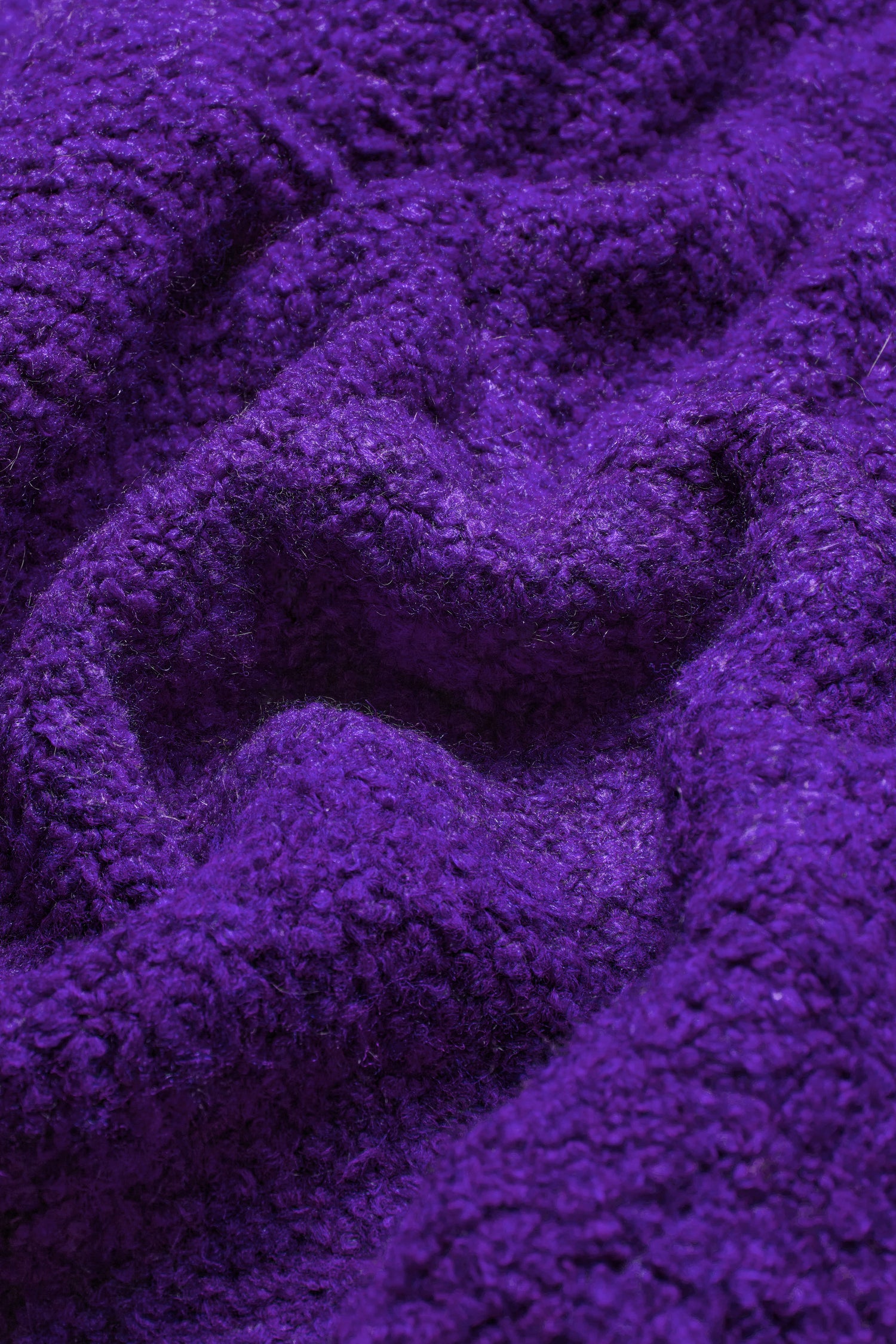 Close-up of a textured purple Bouclé knit fabric with a soft, fuzzy surface and irregular folds, perfect for creating an exquisite Boucle Knit Cable Trim Cardi.