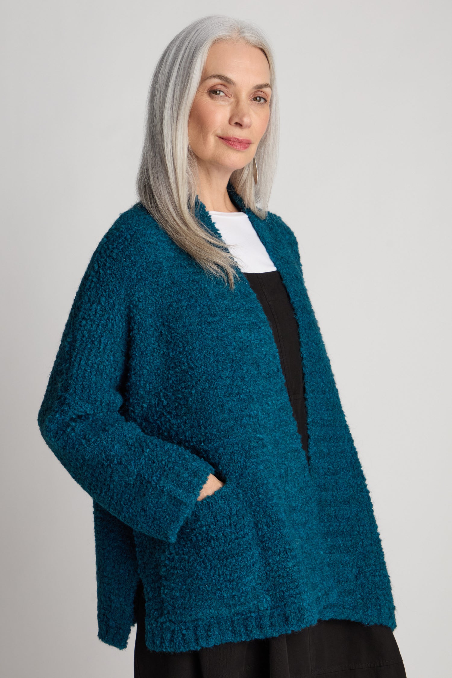 Woman with long gray hair wearing a Bouclé Knit Cable Trim Cardi in blue and a black top, standing against a plain background.