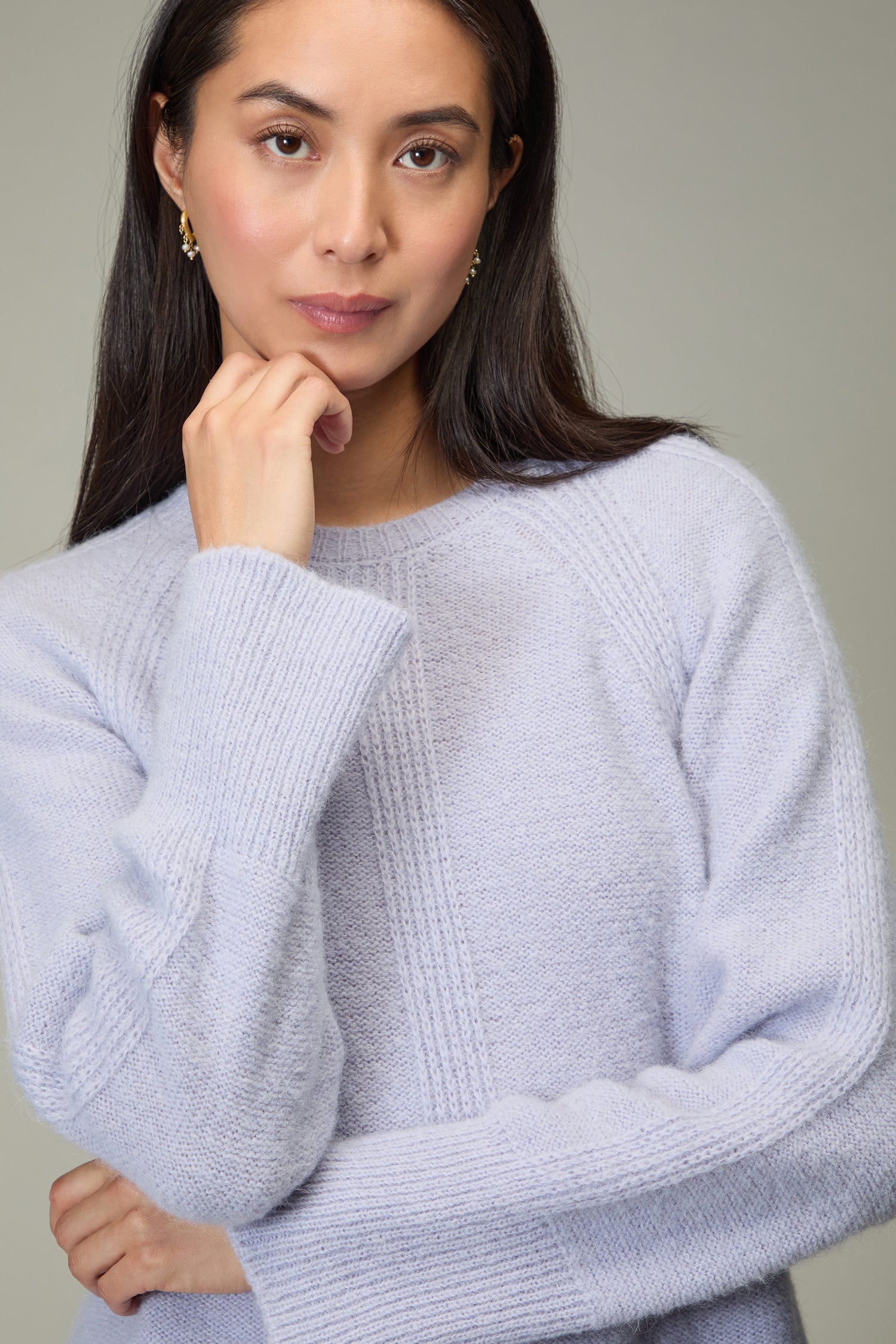 A woman with long dark hair wears the Alpaca Blend Seam Detail Jumper, standing against a plain background, resting her chin on her hand and looking at the camera.
