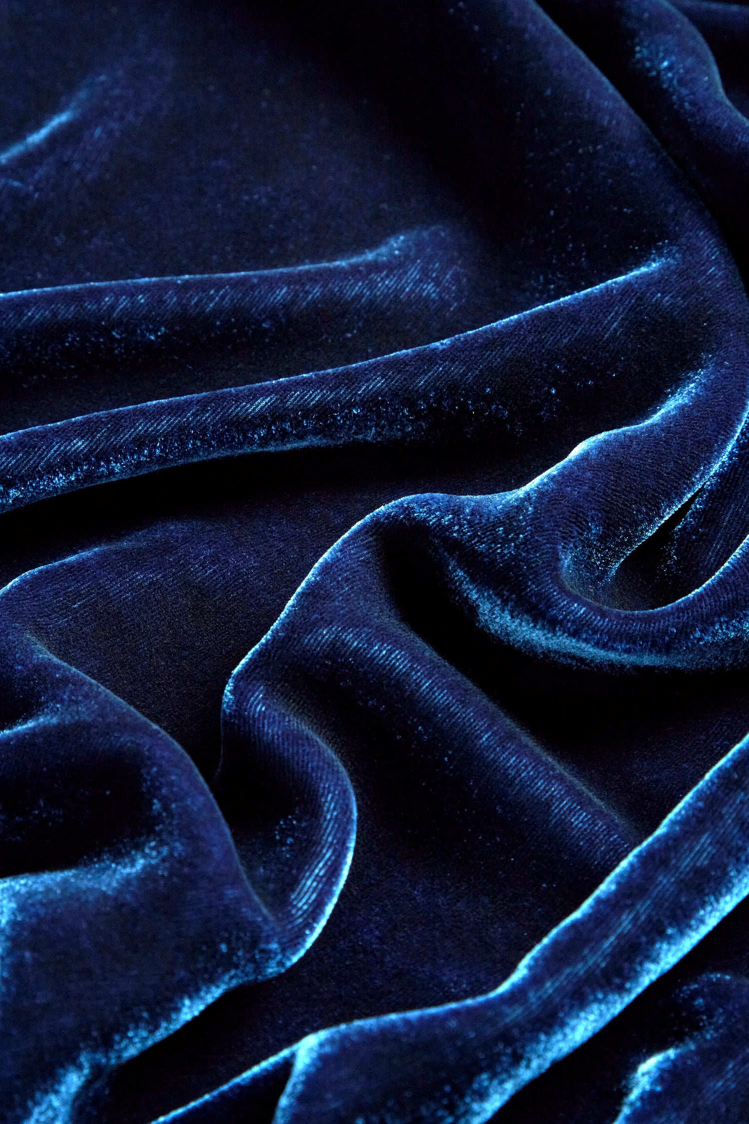 Close-up of the Cowl Silk Velvet Dress fabric, showcasing its dark blue silk velvet material with soft folds and a smooth, shiny texture, ideal for creating an opulent look.