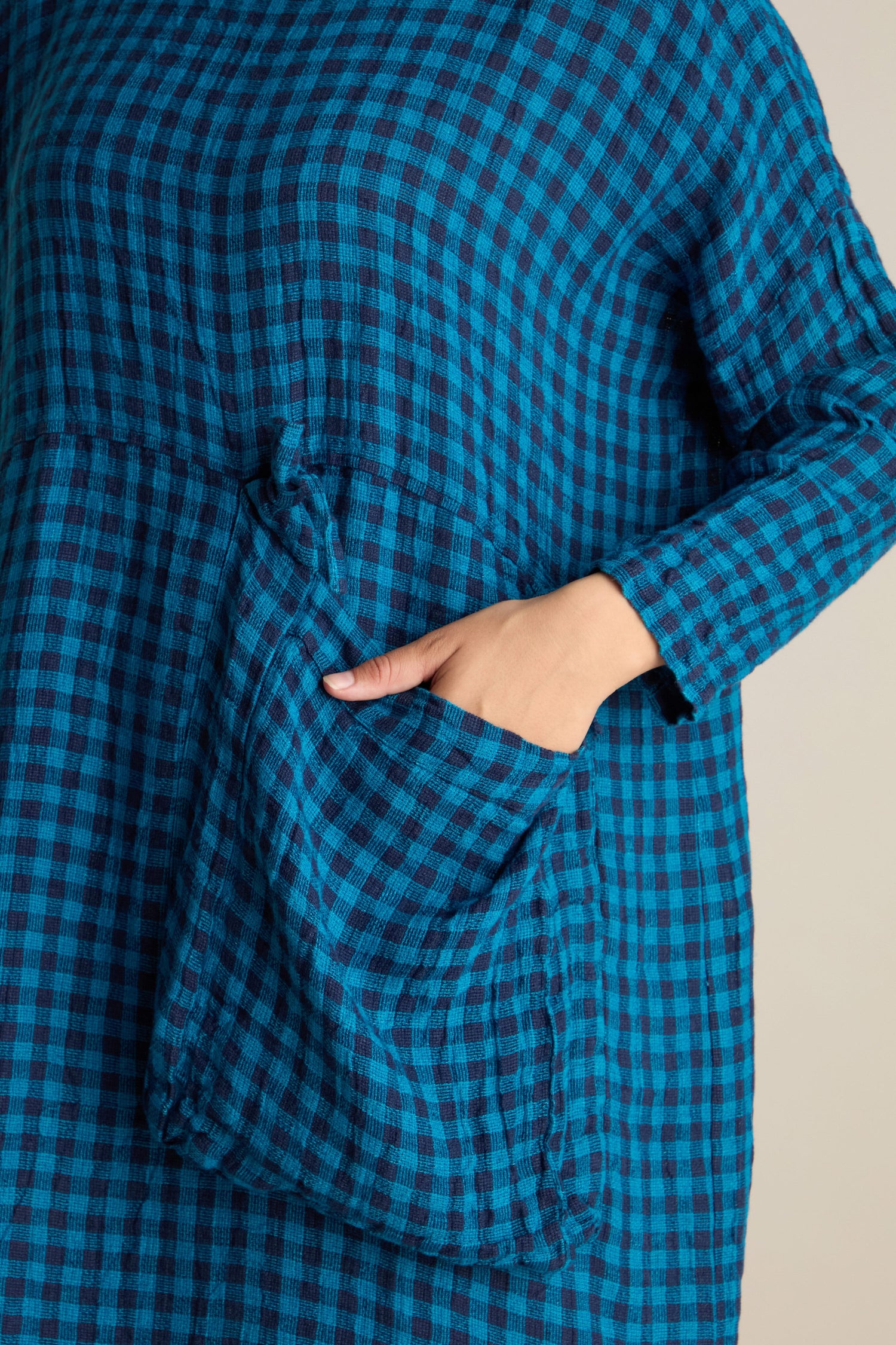 Person wearing the Linen Check Big Pocket Dress featuring a blue and black plaid pattern, made from soft linen fabric, with an oversized pocket and their left hand tucked inside.