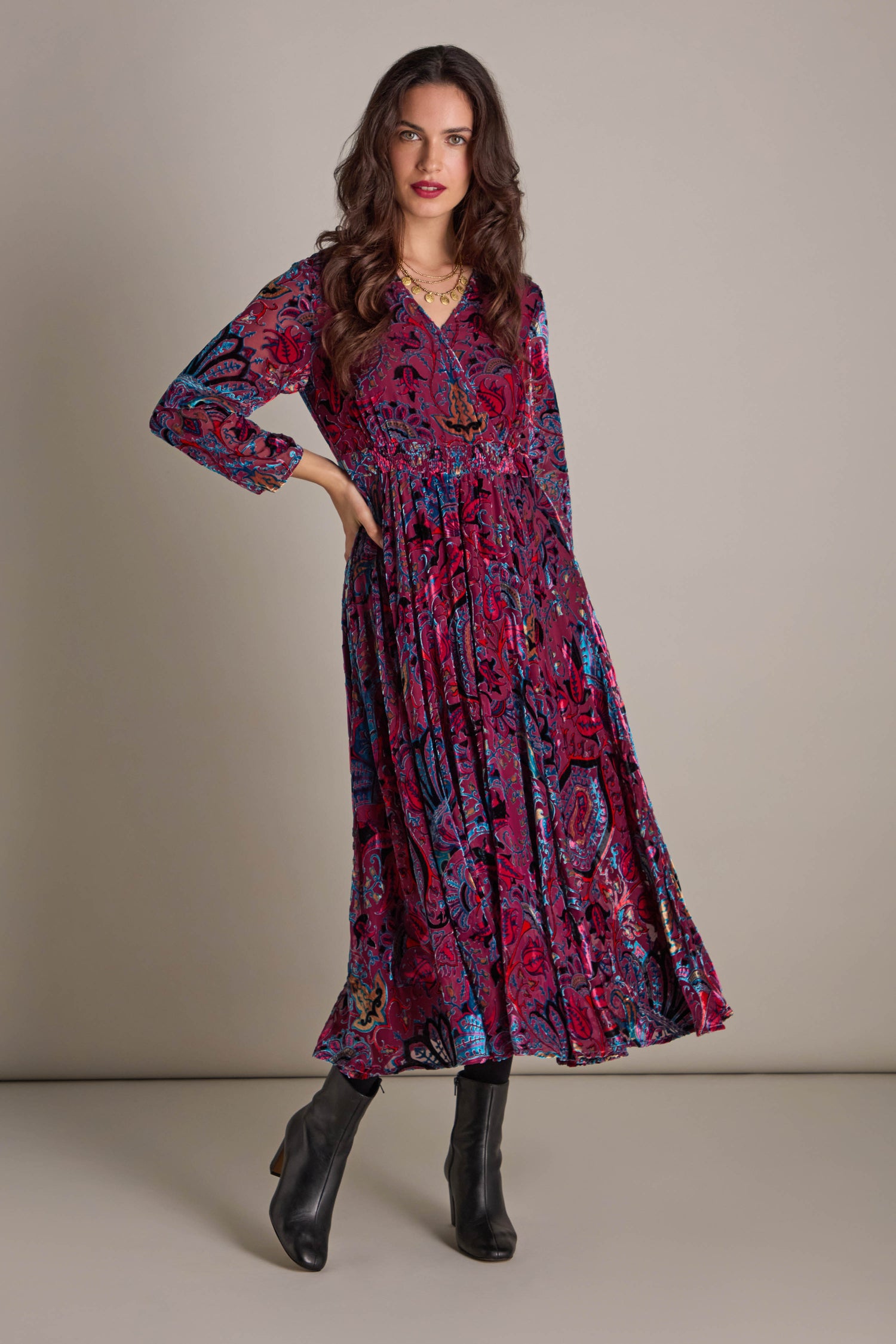 A person in a colorful Winter Paisley Devore Flared Dress paired with black boots stands against a plain background.