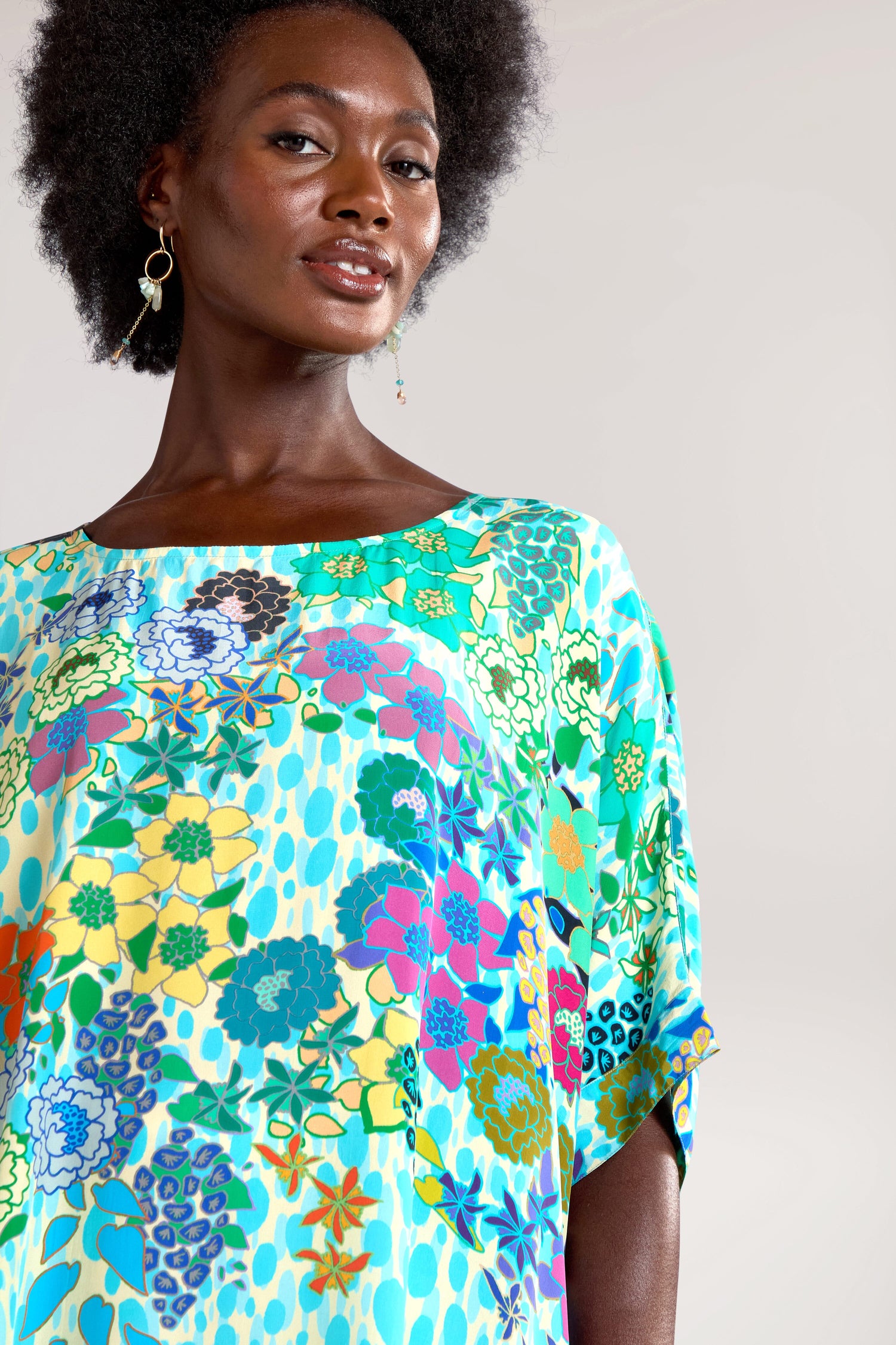 Person wearing a vibrant Garden Spot Tunic and drop earrings, standing against a plain background.