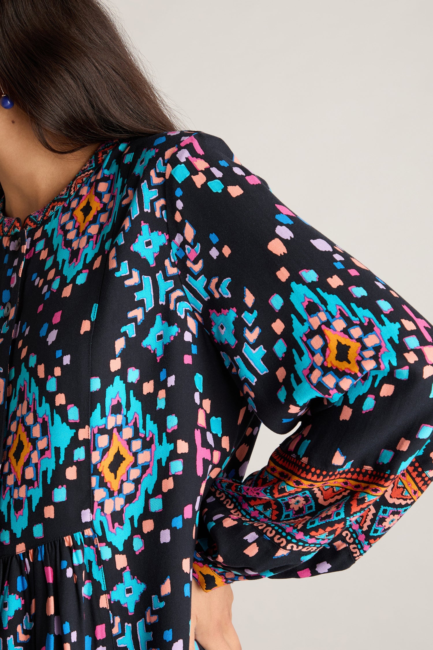 Close-up of a person wearing the Geo Kilim Tunic with long sleeves, showcasing vibrant blue, pink, orange, and black designs in a striking geometric pattern.