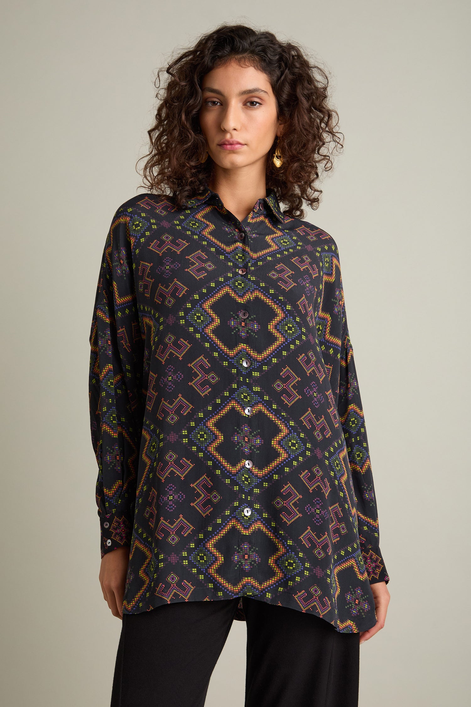 A person with curly hair wears an oversized, boxy fit Pixelated Jacquard Print Shirt, standing against a plain background.