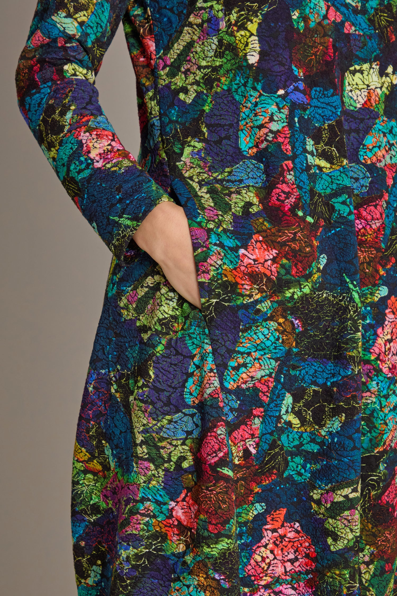 A close-up of the Abstract Floral Jersey Bubble Dress highlights its intricate abstract floral print, with a person's hand casually tucked into the pocket.