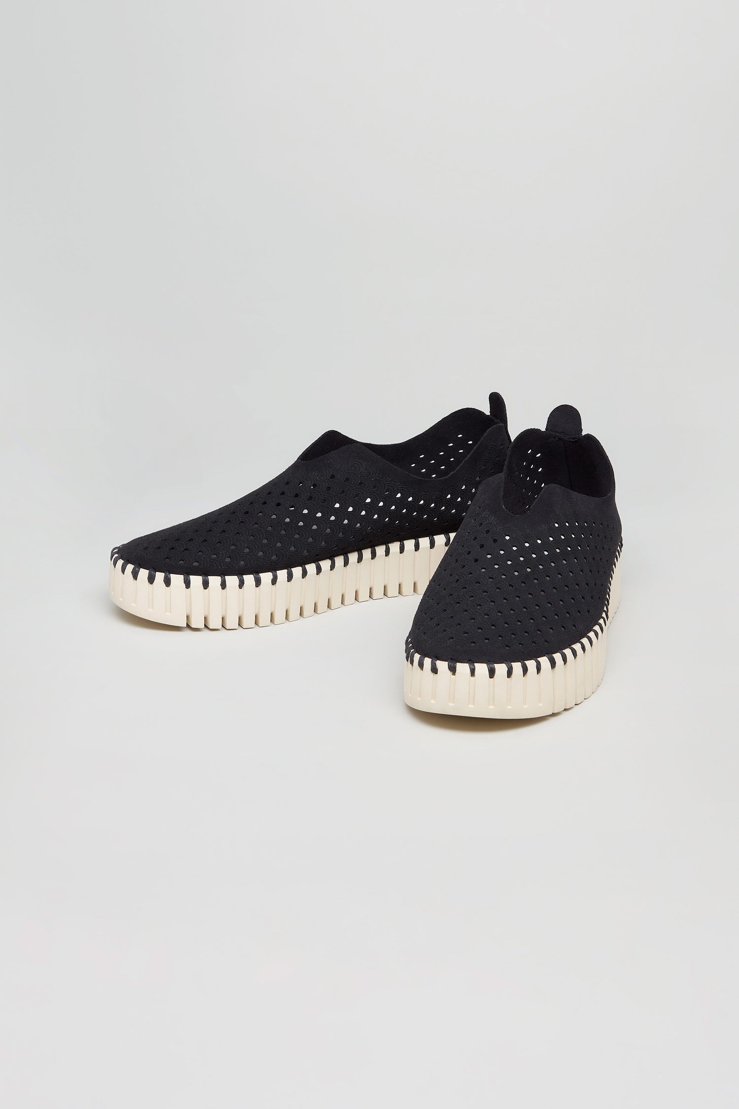 A pair of Black Tulip Platform Slip On Shoes with black perforated uppers and white, ridged soles sits on a plain light background.