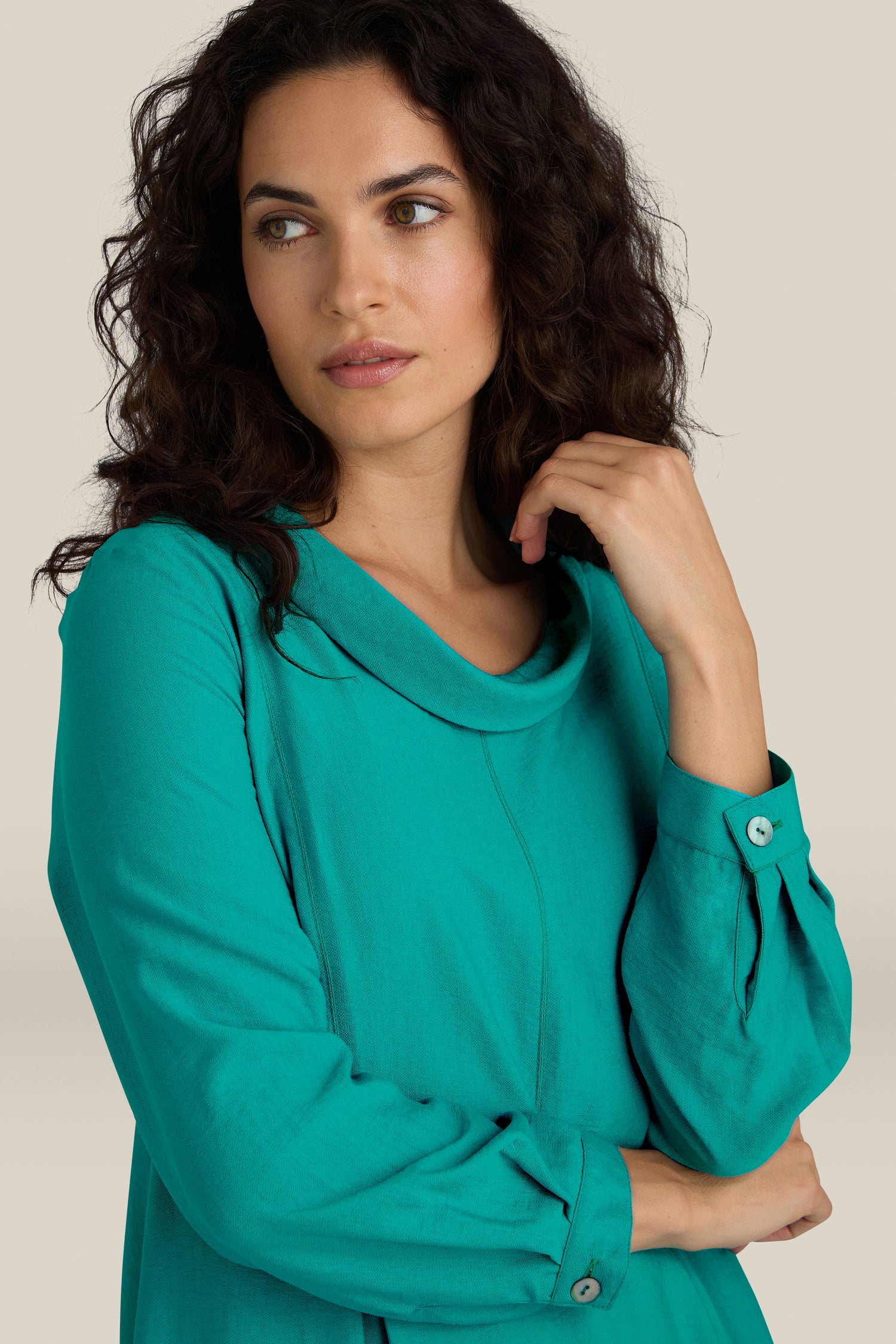 A woman with curly hair in a Textured Viscose Bubble Dress strikes a pose with her hand touching her neck against a plain background, exuding everyday elegance.