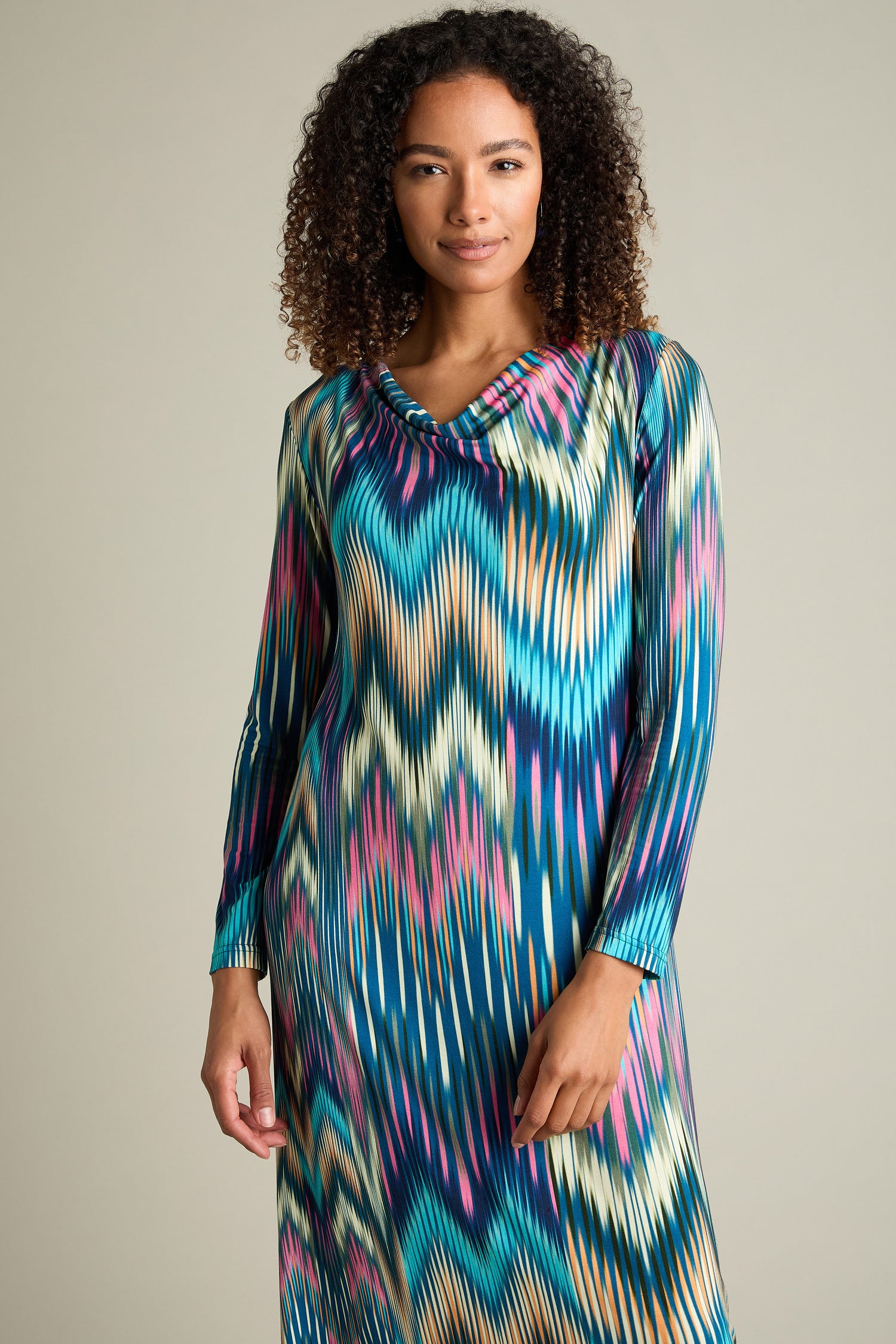 A person with curly hair wearing the long-sleeved Autumnal Ikat Jersey Dress stands against a plain background.