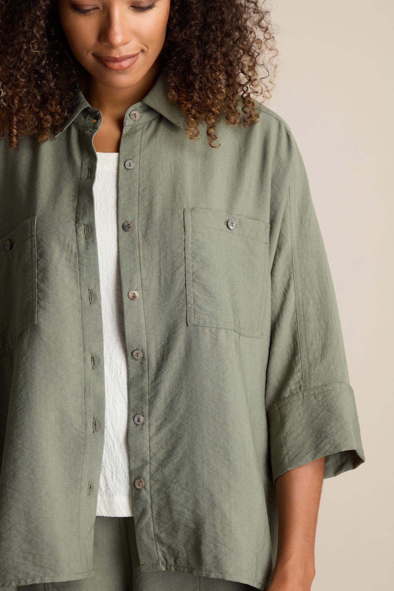 A person is wearing a Textured Viscose Boxy Shirt over a white top. They have curly hair and a neutral expression, with only their upper torso visible.