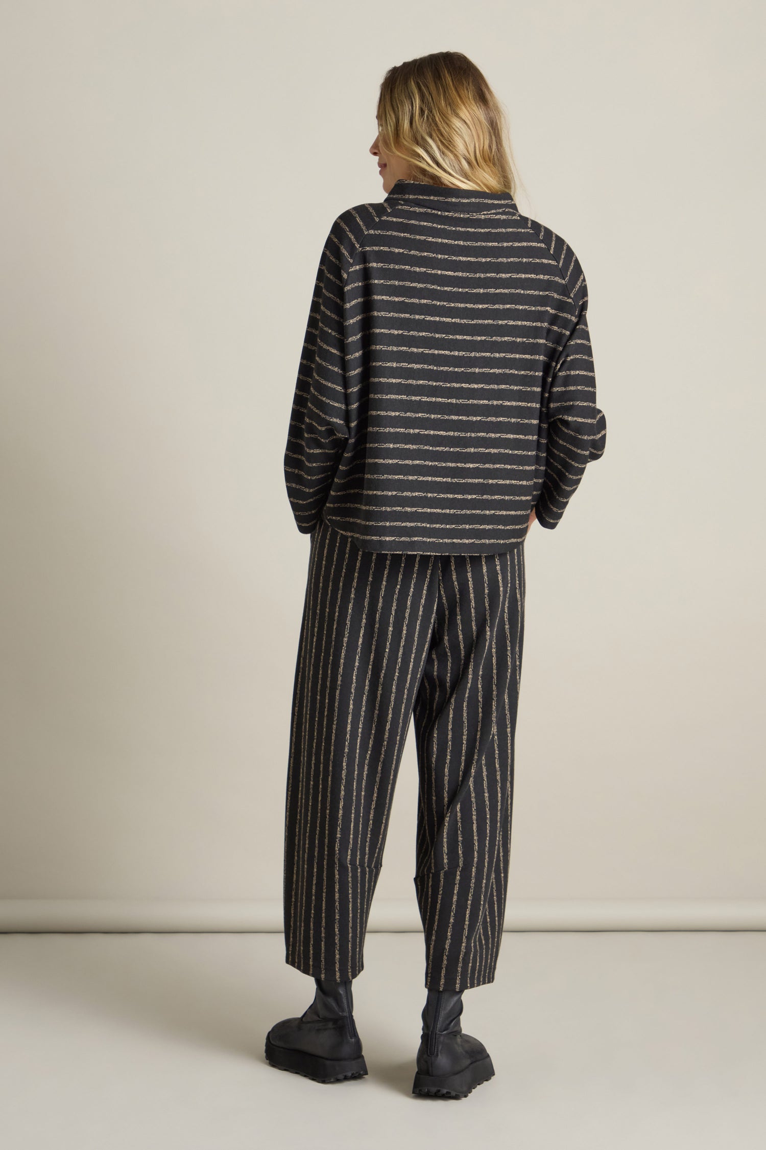 Person standing against a plain background, wearing the Broken Stripe Jersey Top with dolman sleeves and matching wide-legged pants, with their back turned to the camera. They are also wearing dark shoes.