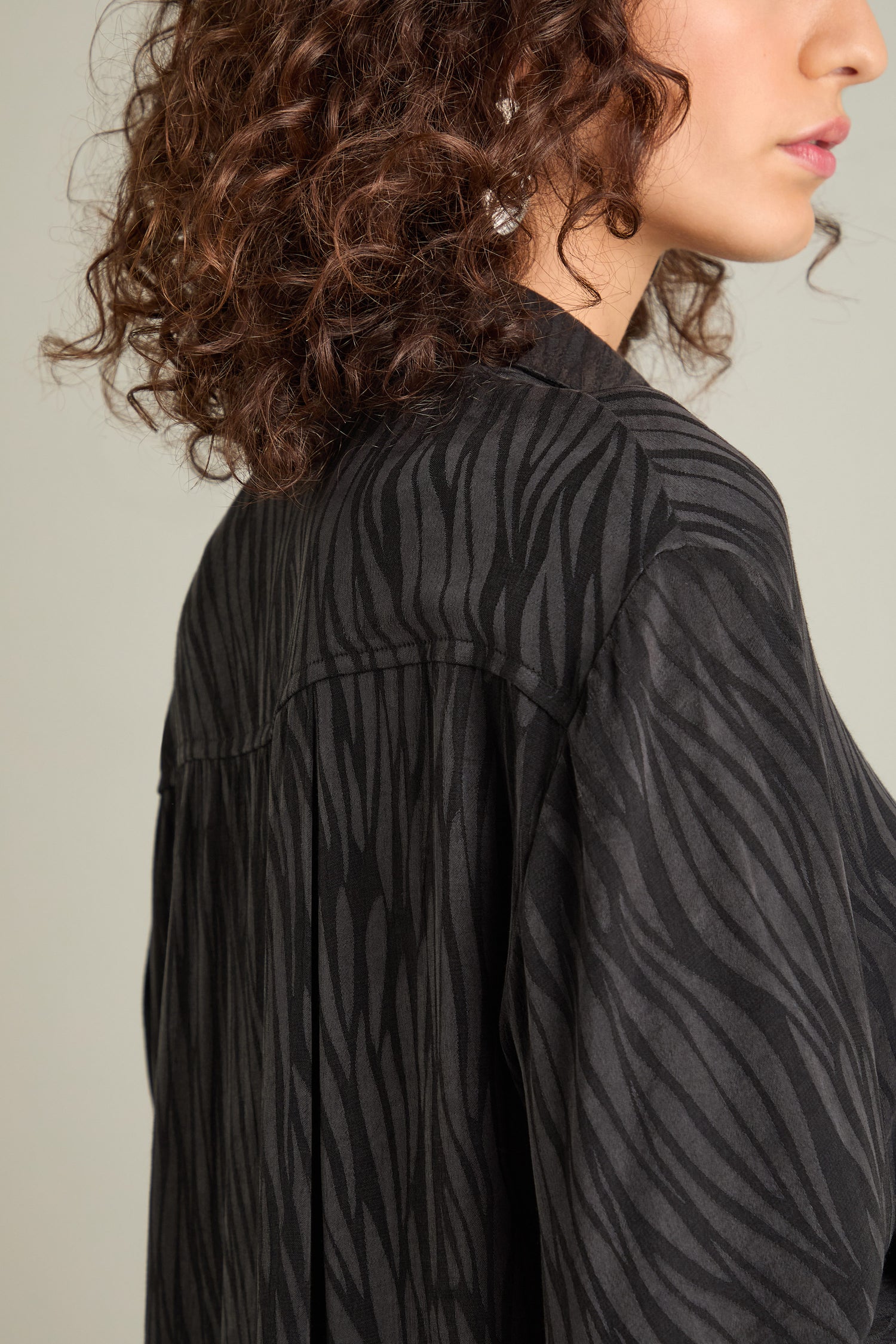 Close-up of a person with curly hair wearing the relaxed-fit Abstract Lines Jacquard Long Shirt, showing their side profile.