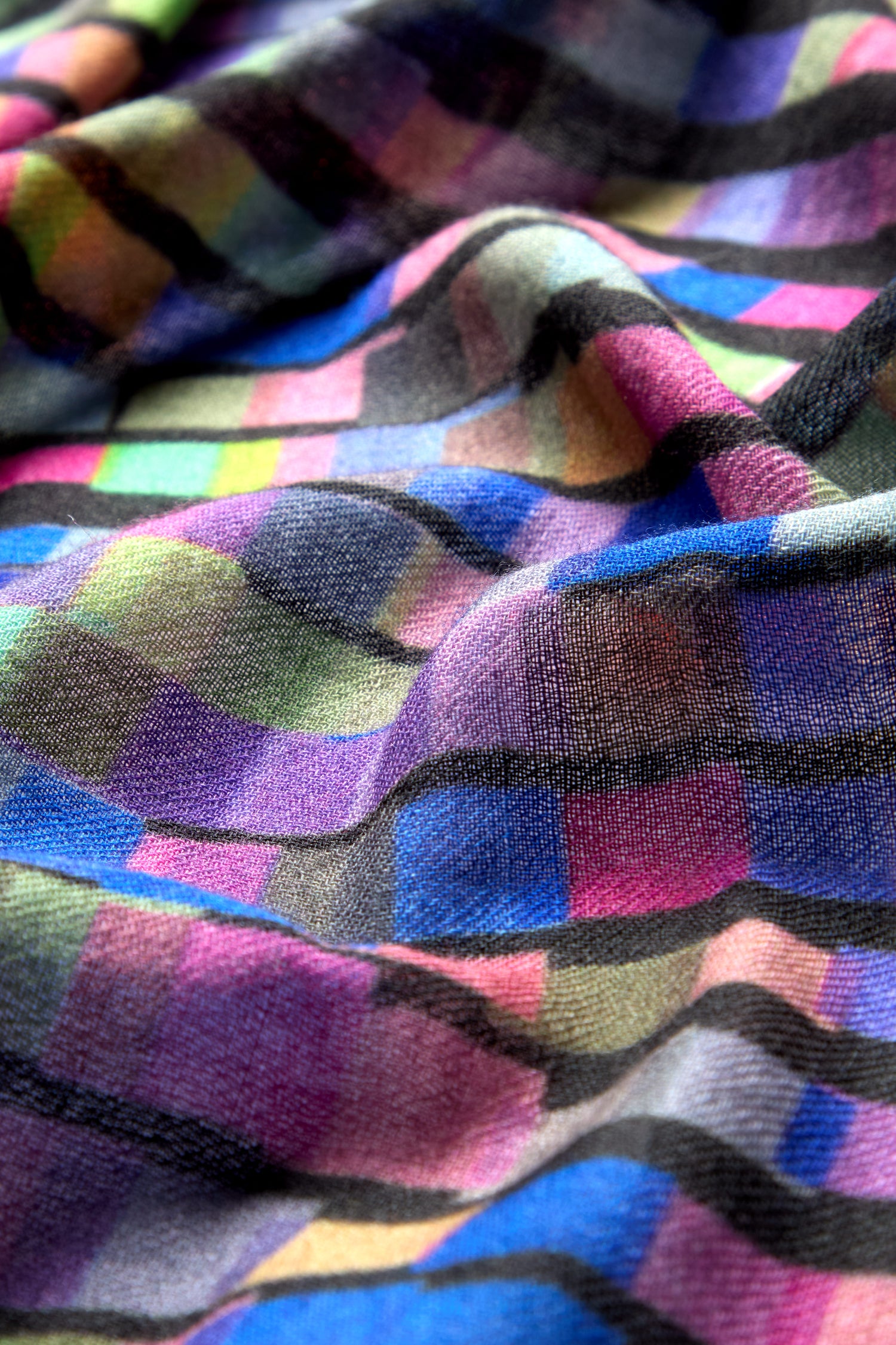 Close-up of the Graduated Rainbow Squares Wool Scarf, showcasing its premium wool material and multicolored, checkered fabric with a soft, draped texture. The vibrant rainbow squares display shades of purple, blue, green, and black.