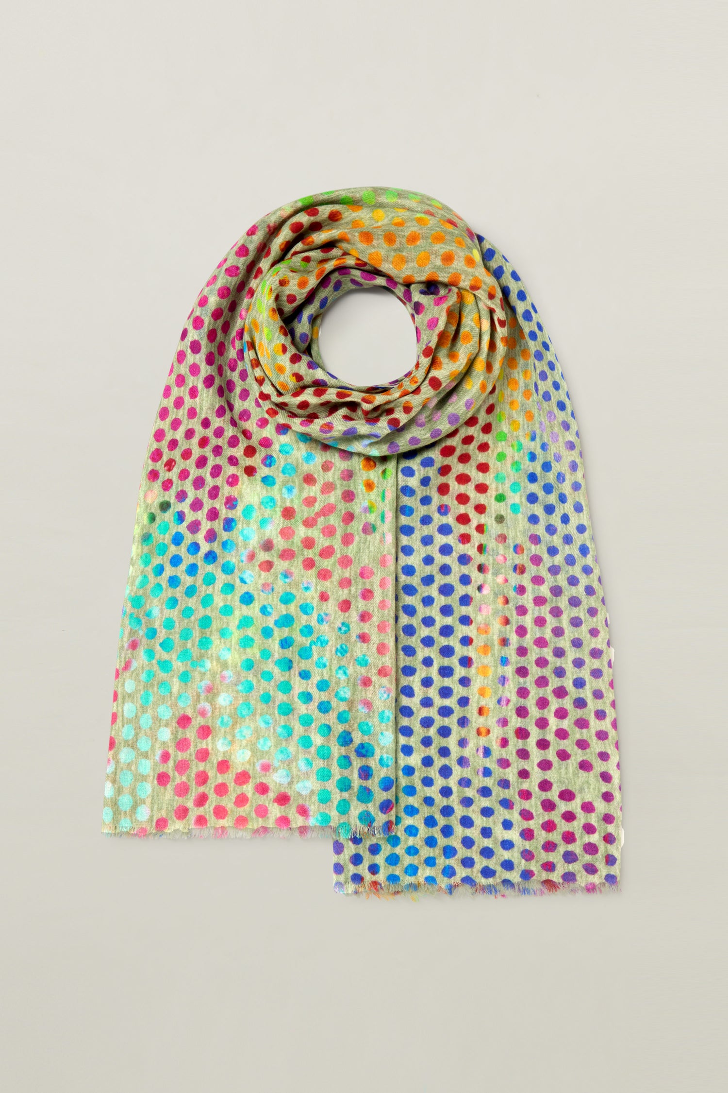 A vibrant Mini Rainbow Spot Merino Wool Scarf adorned with a polka dot pattern in shades of red, blue, green, yellow, and purple, laid out flat on a light grey background. This colorful accessory is sure to brighten up any outfit.