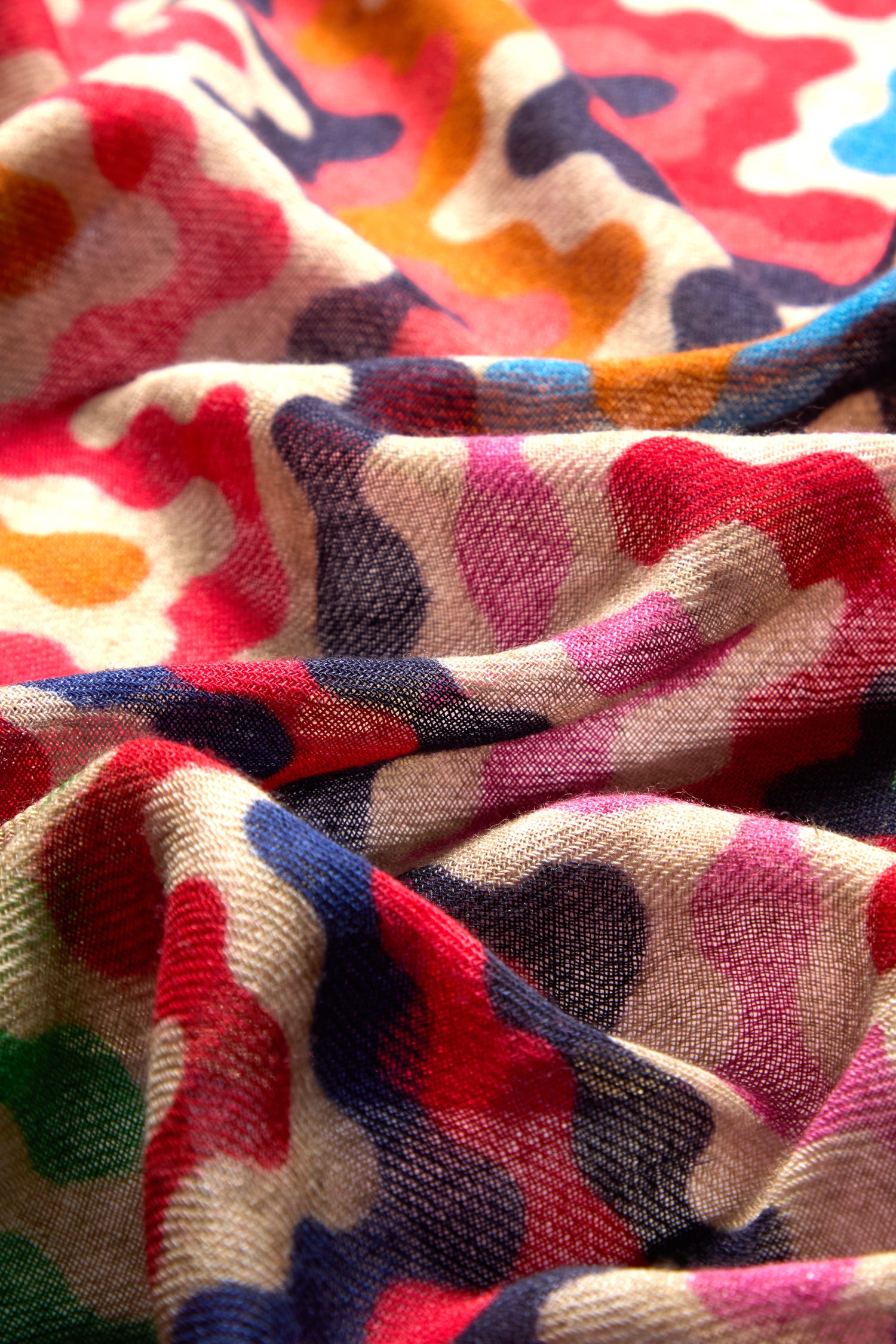 Close-up of a colorful, psychedelic wavy design on the premium Reverie Print Wool Scarf, showcasing shades of red, pink, blue, green, and beige. This mesmerizing pattern is part of the exquisite collection.