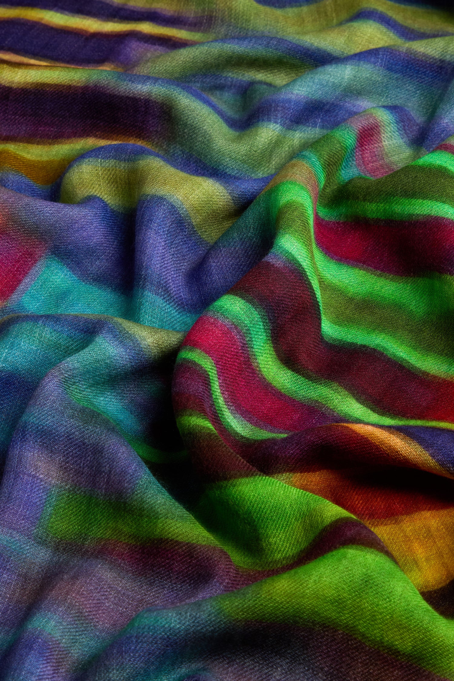 The Brushstroke Stripe Wool Blend Scarf boasts a vibrant pattern with colorful stripes in blue, green, red, and yellow tones, ideal for versatile styling.