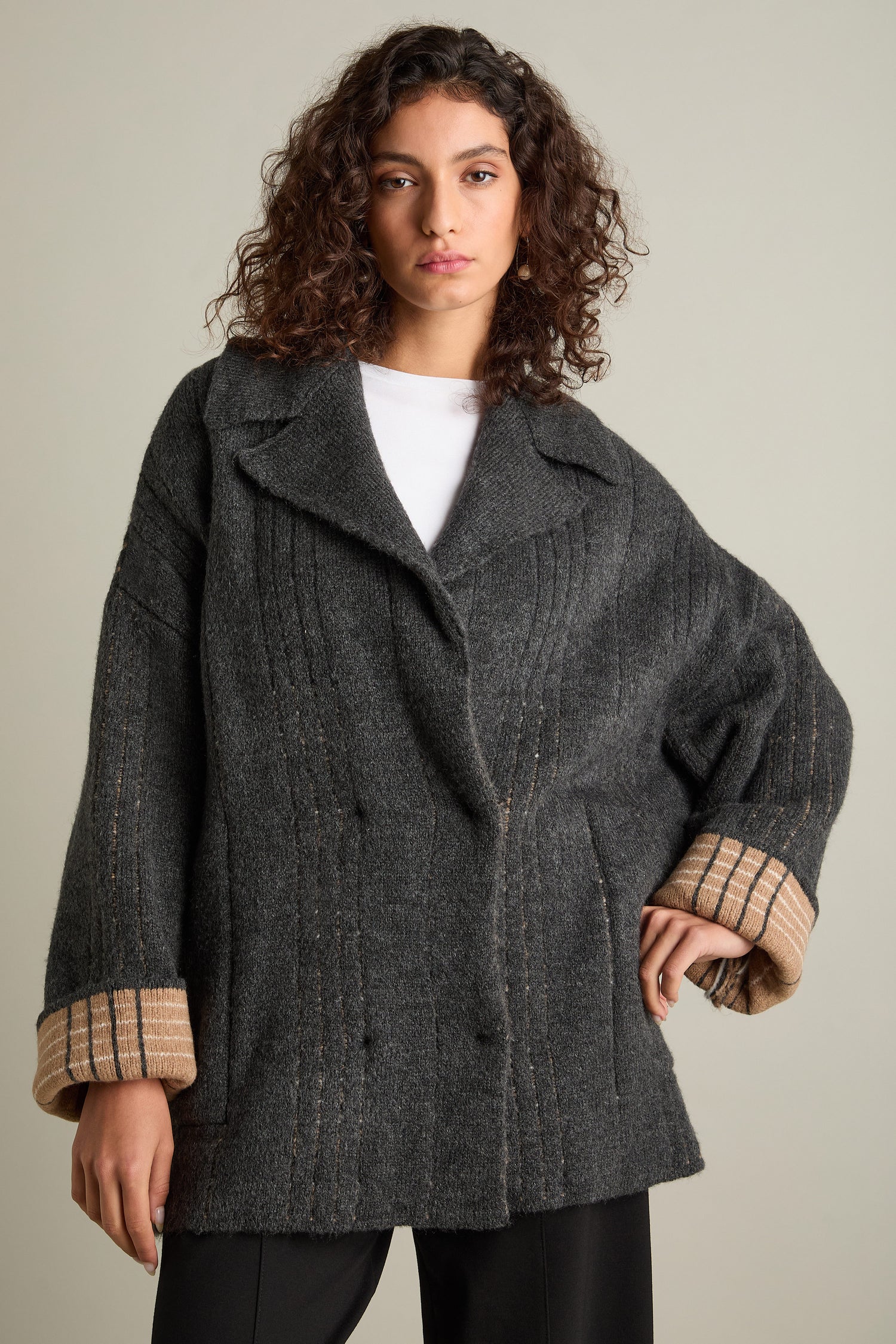 The woman with curly hair is wearing a Check Detail Jacket, an oversized dark gray wool blend coat that's perfect for layering, with stylishly turned-up sleeves.