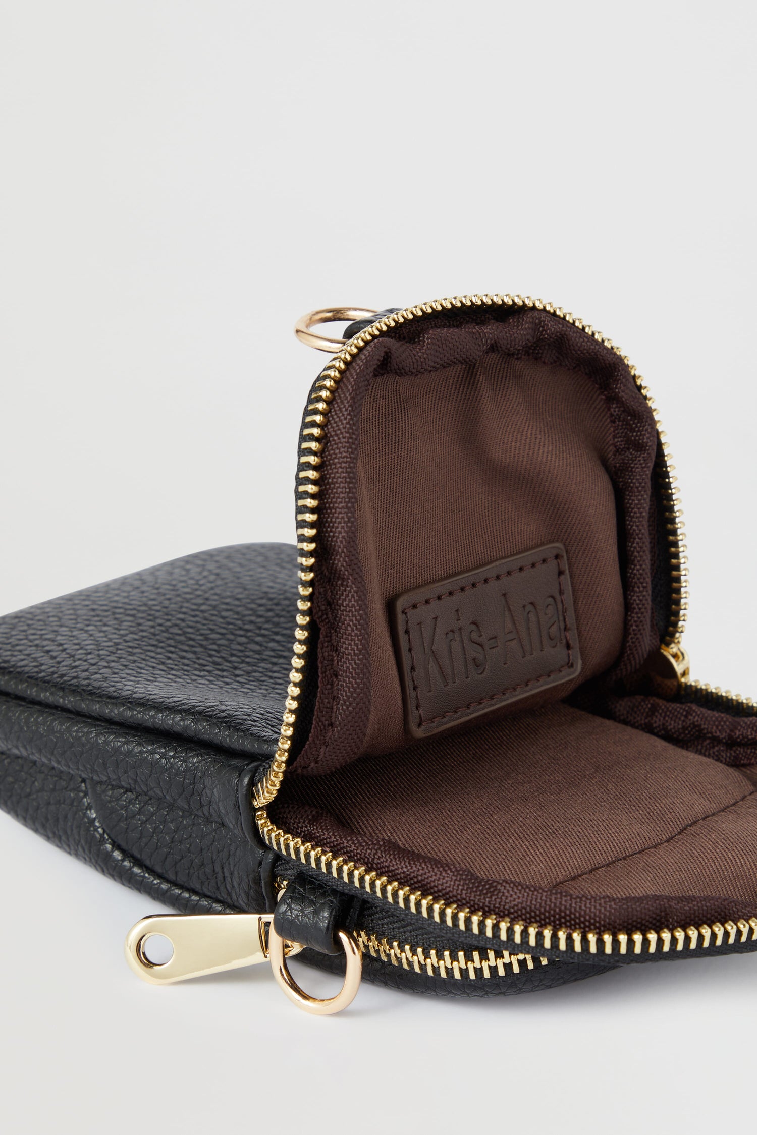 A Kris-Ana black zippered mini crossbody bag with a gold zipper, featuring style-led designs.