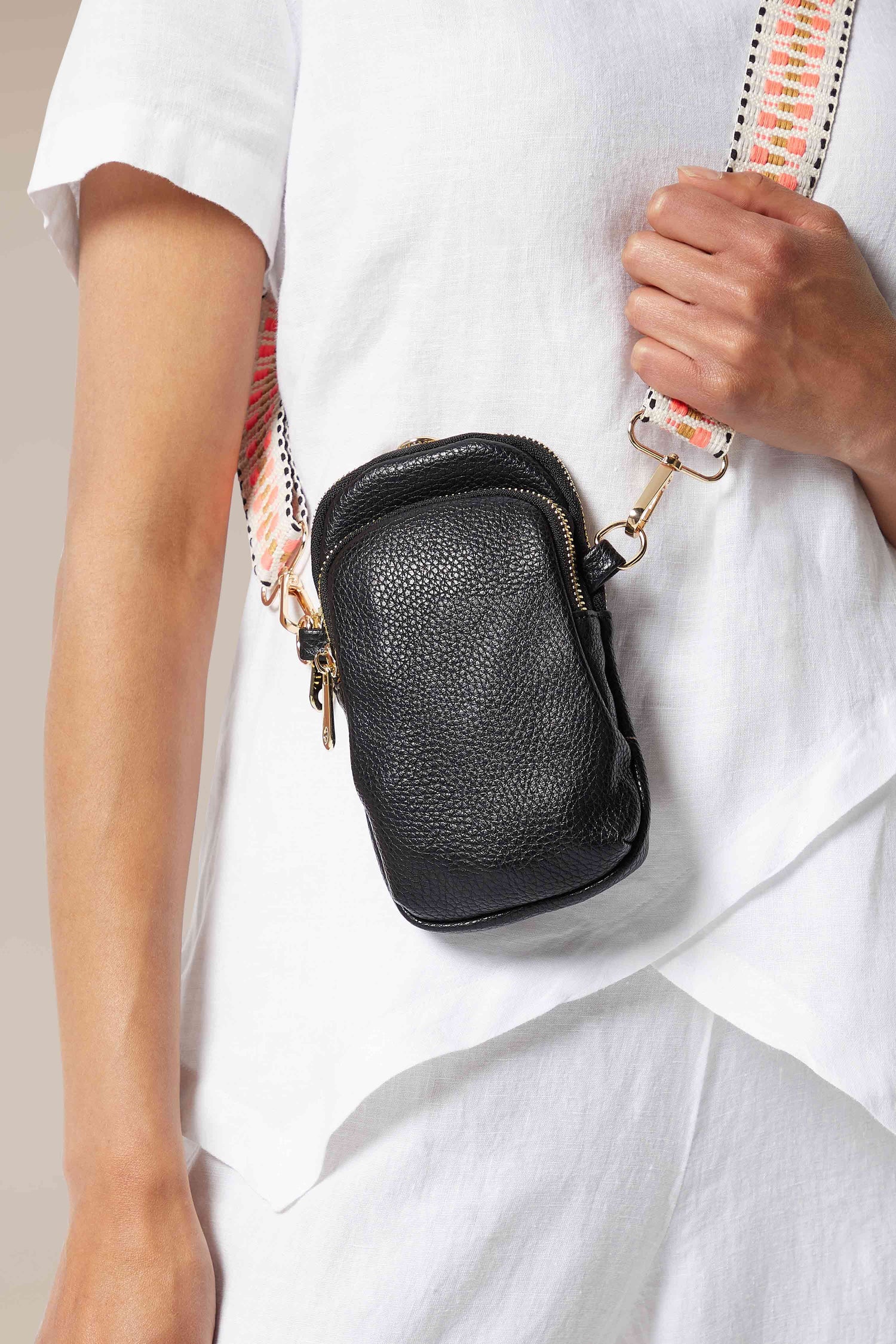 A woman is holding a stylish Kris-Ana black Mini Crossbody Bag.