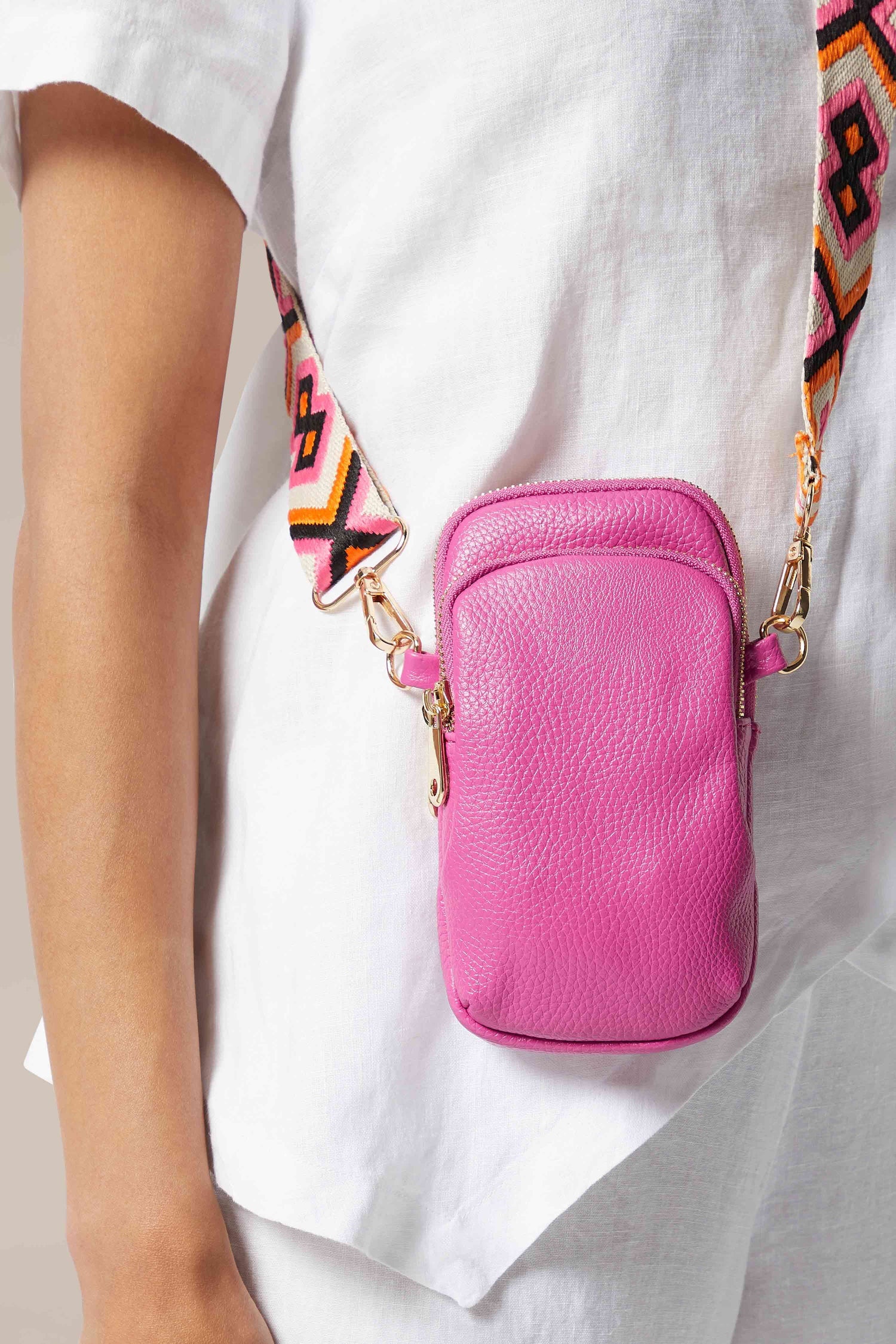 A woman is holding a Mini Crossbody Bag in pink, showcasing their stylish and design-led designs.