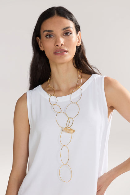 A person with long dark hair wearing a sleeveless white top and a large Handmade Crystal Quartz Rings Necklace stands against a neutral background.