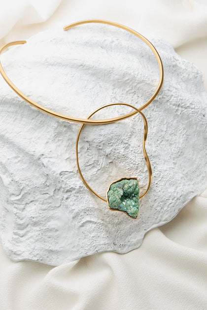 Introducing the Handmade Agate Hoop Necklace: a stunning choker crafted from 24k gold plated brass, with an irregularly shaped semi-precious green agate pendant beautifully displayed against textured white fabric.