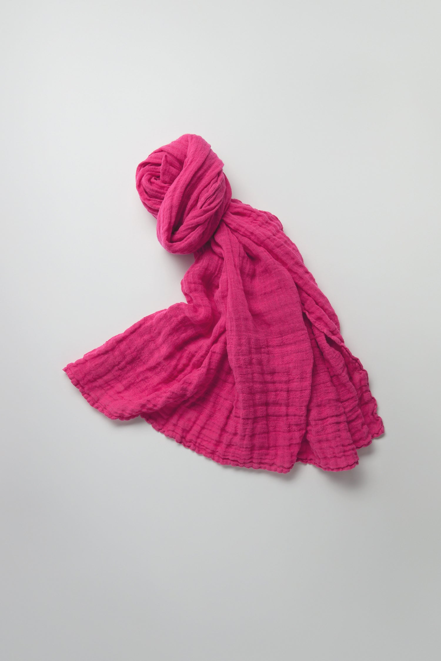 A Crinkle Linen Scarf, vibrant and lightweight, rests crumpled against a plain white background, highlighting its potential as an accessory.