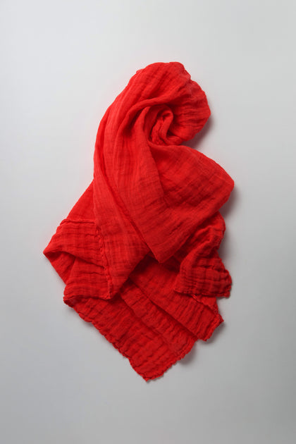 A crumpled red Crinkle Linen Scarf rests elegantly on a white background, highlighting the charm of this lightweight accessory.