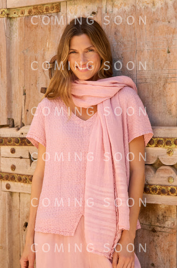 A woman in a light pink top, Crinkle Linen Scarf, and skirt stands before a wooden door. "COMING SOON" is displayed over the image.