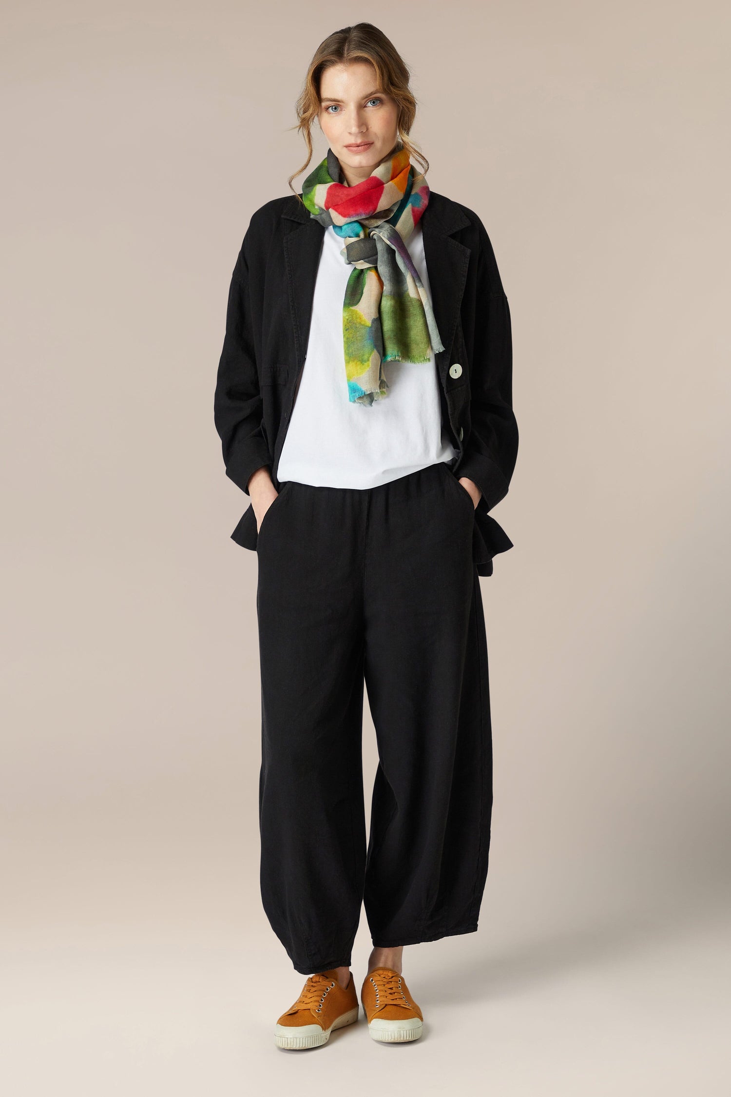 A woman wearing black Twisted Linen bubble trousers with an elasticated waistband and a colorful scarf.