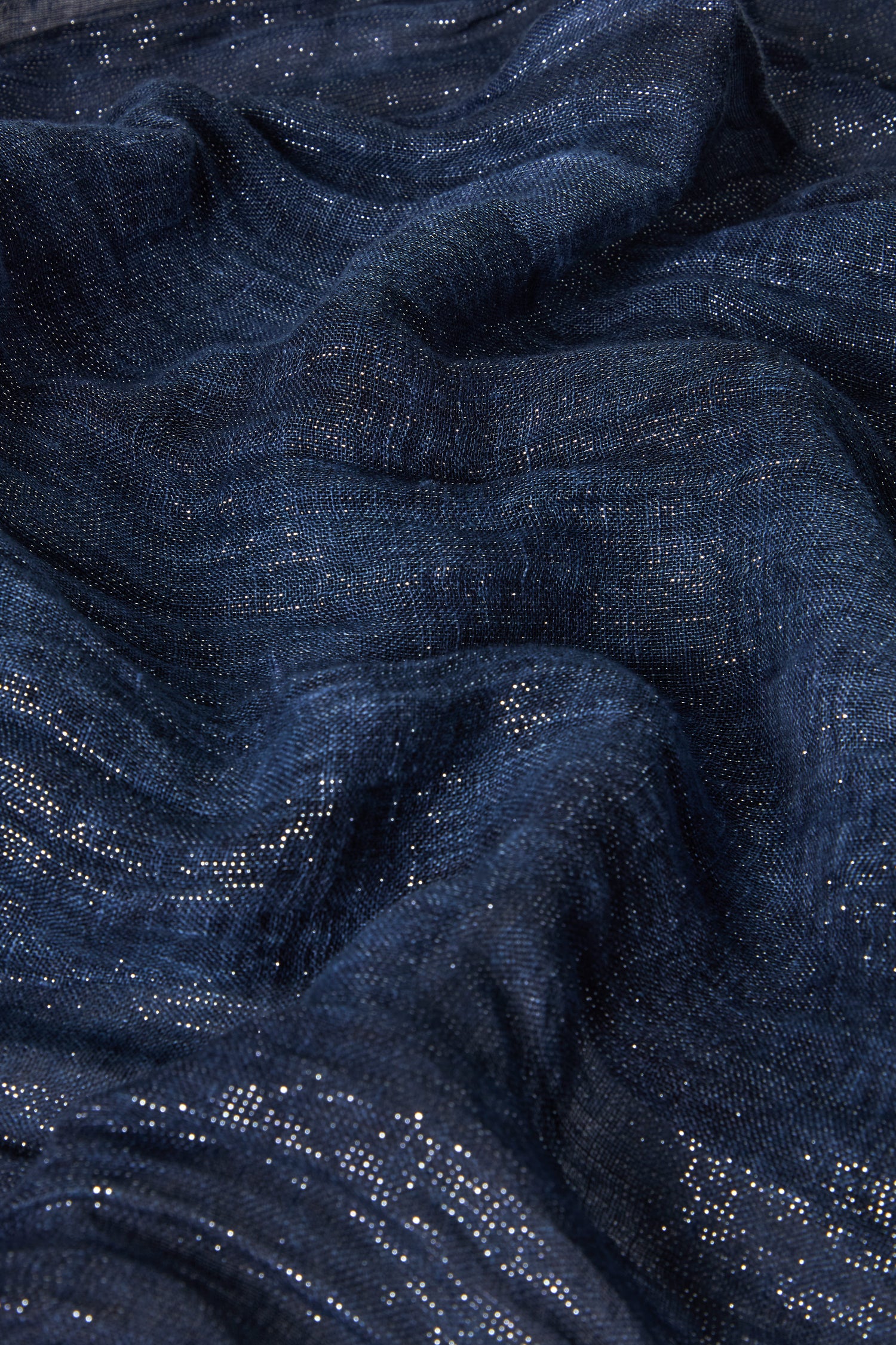 A detailed view of the Starry Night Scarf's indigo blue fabric features metallic threads that shimmer, reminiscent of a textured night sky.