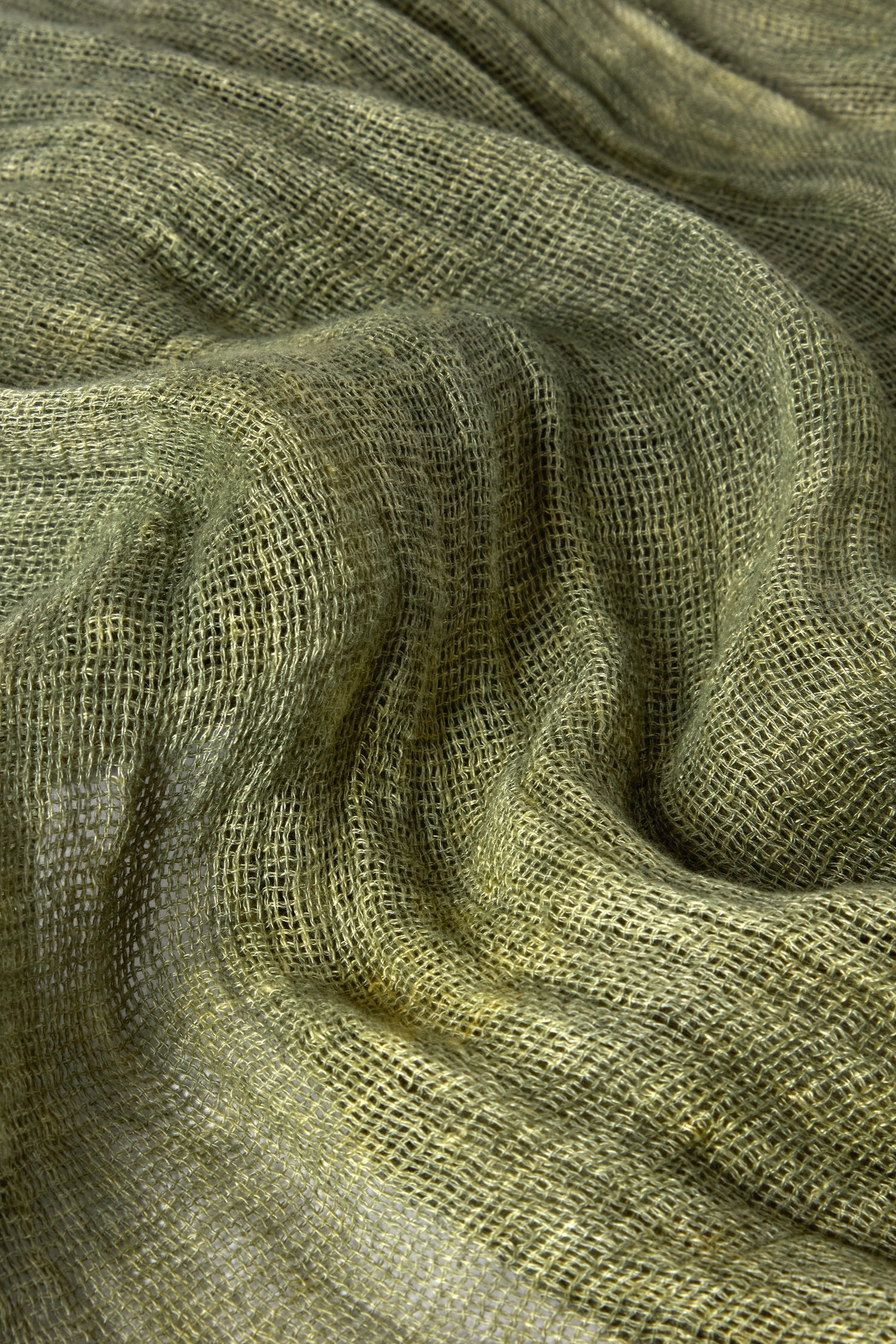 Close-up of a crumpled green Woven Linen Scarf, featuring a textured, woven pattern. Made from 100% linen with natural fiber, it brings rustic charm to the raw-edge finish.