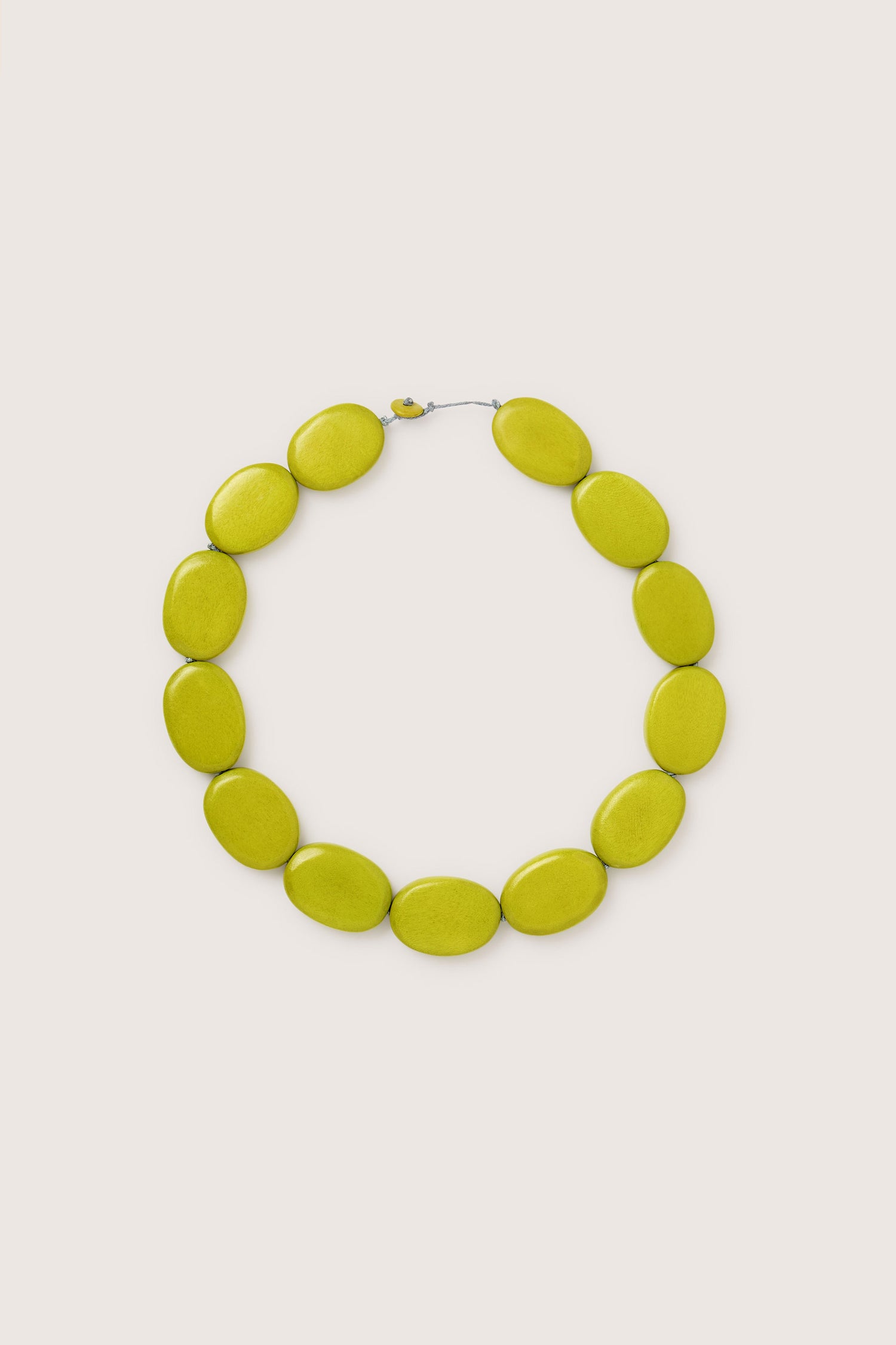 The Short Wooden Pebble Necklace, model LFH2113, features large, flat, oval-shaped green beads arranged in a circular pattern.