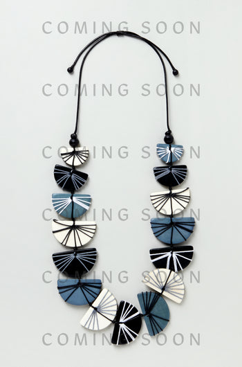 The Fan Necklace (LFHC0324), a blue, black, and white geometric beaded necklace with a cord and bead closure, is displayed on a light background with "Coming Soon" repeatedly overlaid on the image.