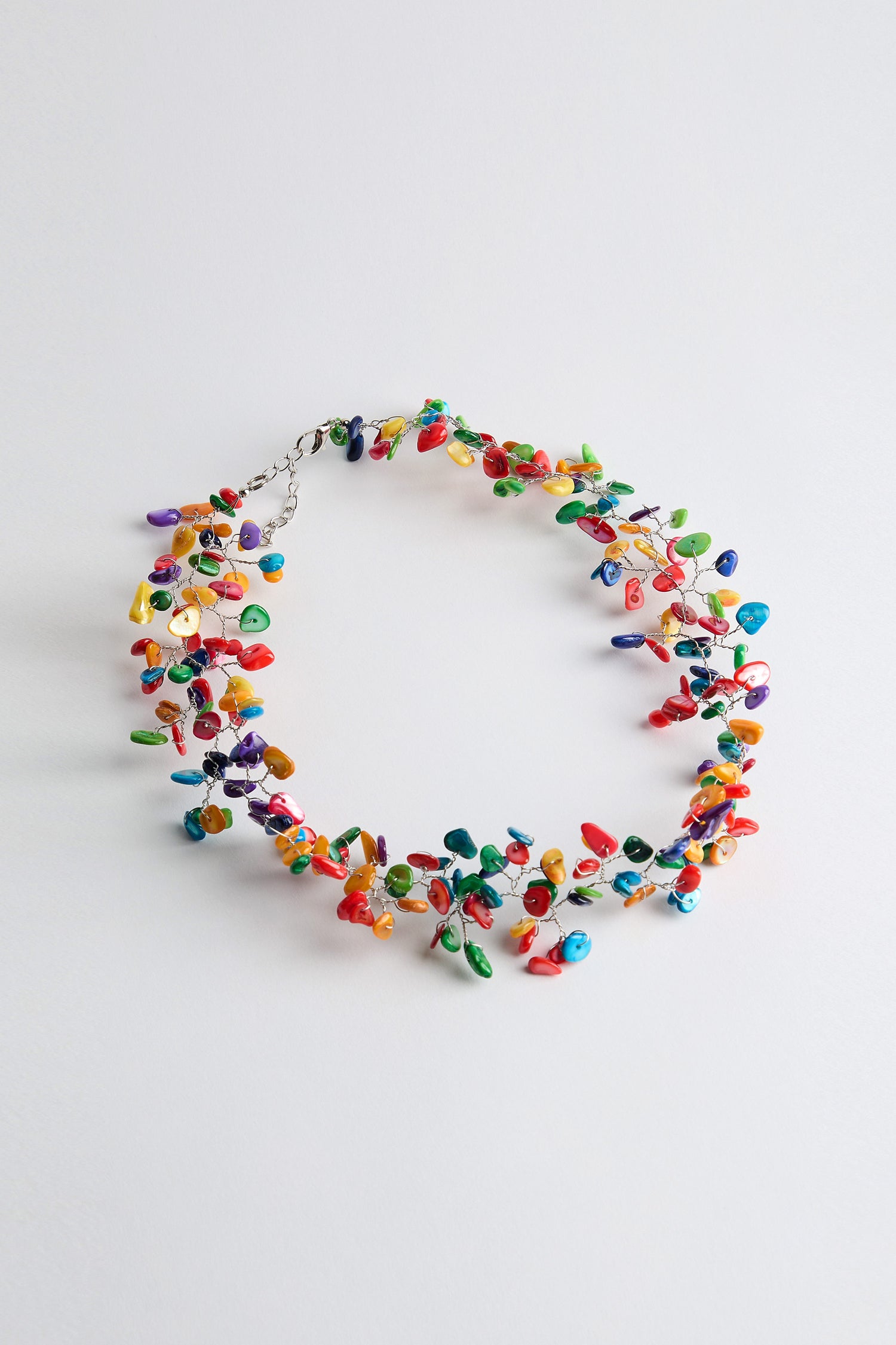 Meet the Rainbow Rivershell Necklace, a striking accessory adorned with colorful, handcrafted river shell beads in diverse shapes and sizes on a pristine white backdrop.