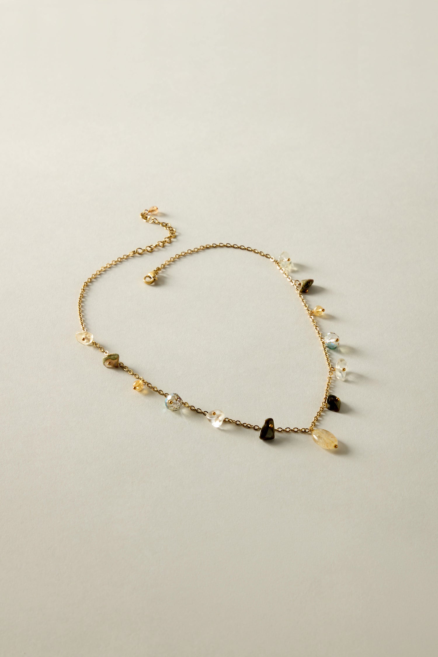 The Citrine and Rhyolite Bead Necklace, featuring small, irregular citrine gemstones, is displayed on a light grey background.