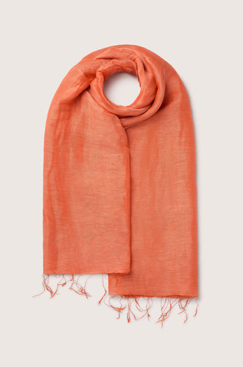 A neatly folded, luxurious Soft Linen Scarf with frayed ends, laid out on a light background.