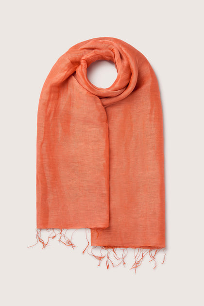 A neatly folded, luxurious Soft Linen Scarf with frayed ends, laid out on a light background.