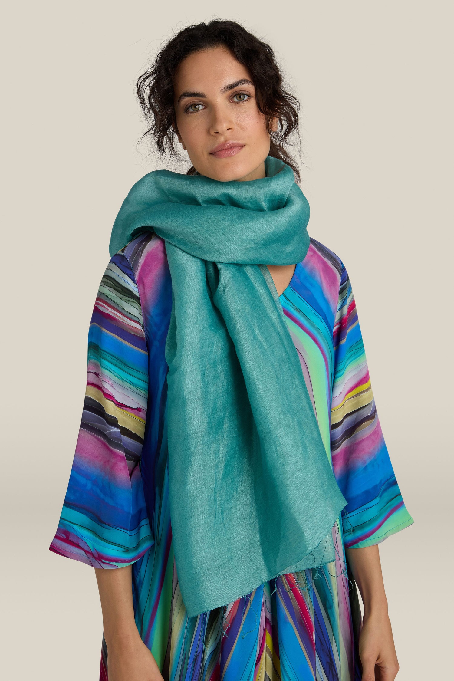 A person wearing a colorful, striped dress and a luxurious Soft Linen Scarf stands against a plain background.