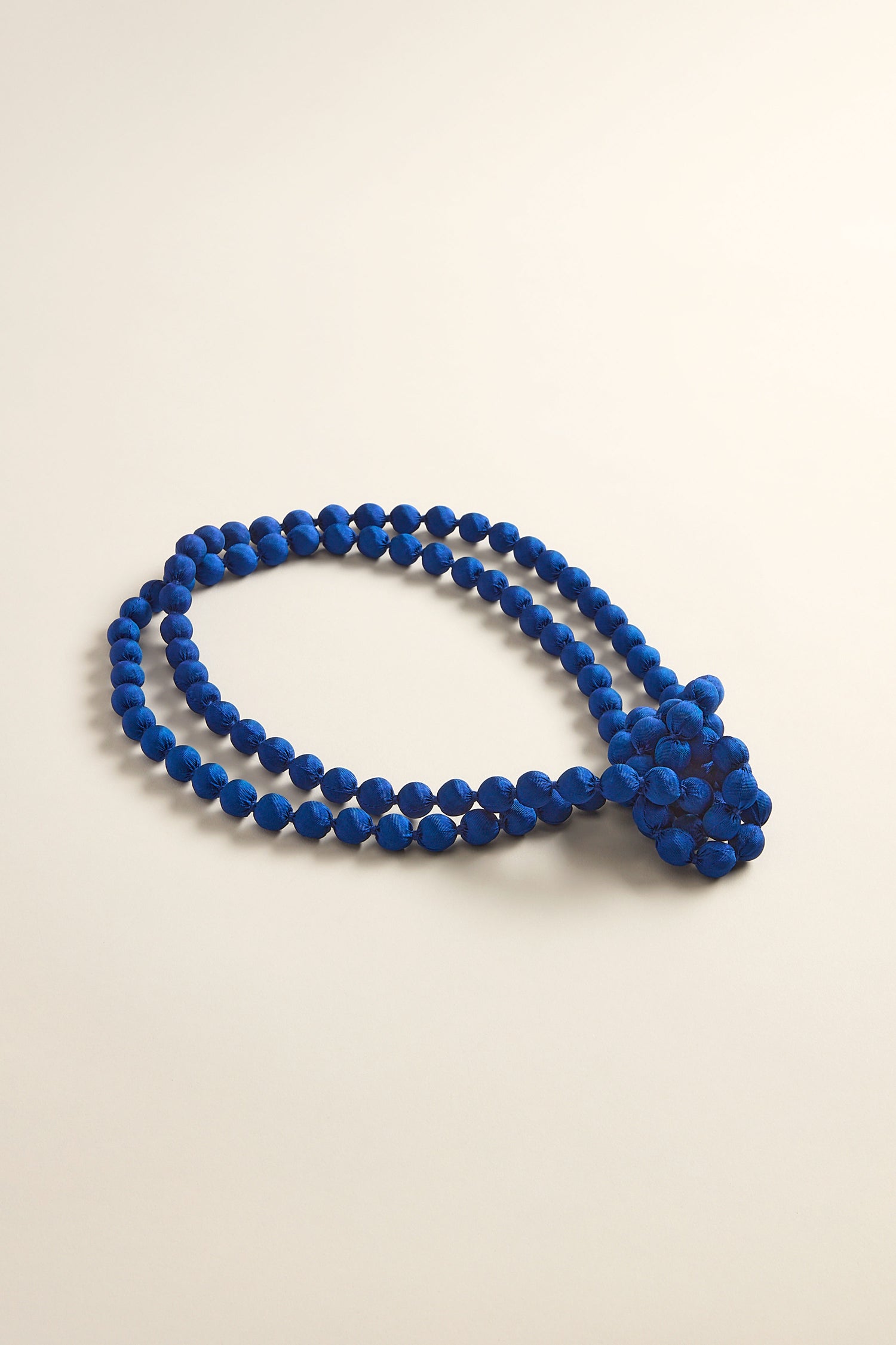 The Handmade Long Silk Spheres Necklace is a double-strand piece that showcases vibrant blue beads, highlighting artisanal craftsmanship against a light background.