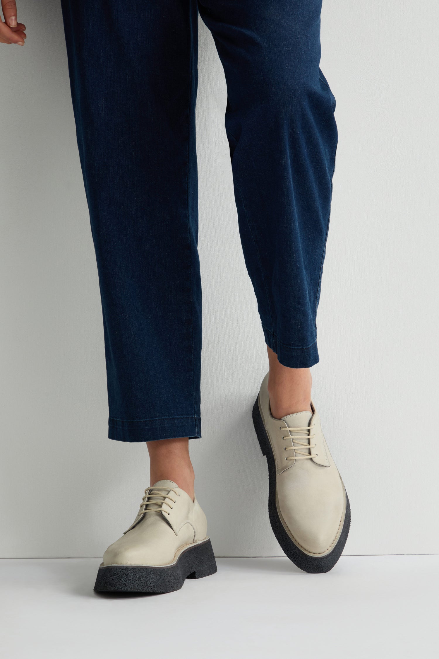 A person stands against a white backdrop, wearing dark blue pants and off-white Lace up Leather Brogues with modern platform soles.