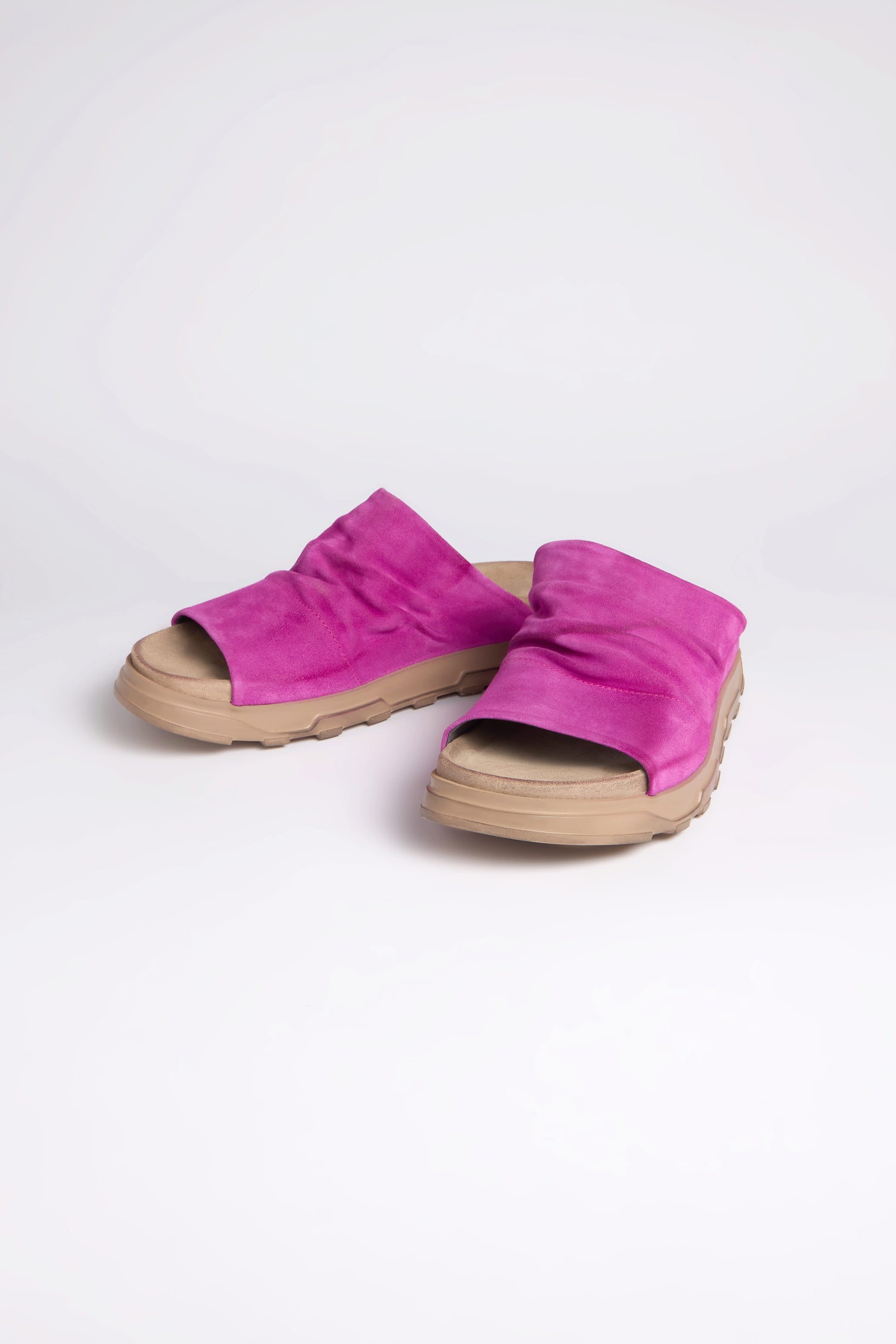 The Magenta Crushed Leather Sliders feature tan rubber soles for all-day comfort, elegantly showcased on a white background.