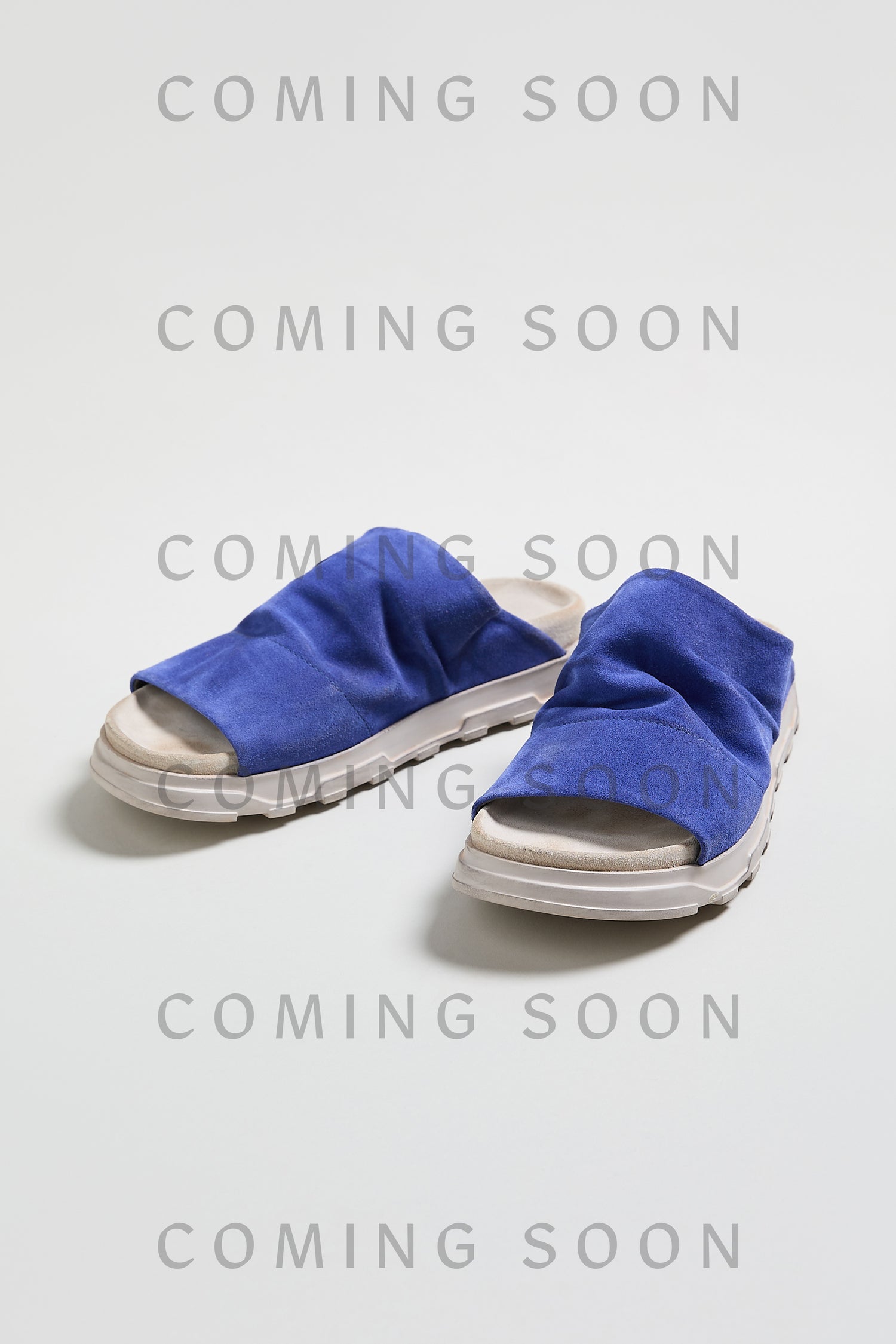A pair of blue Crushed Suede Sliders with white soles, style LOFI3364, on a plain background featuring gray "COMING SOON" text.