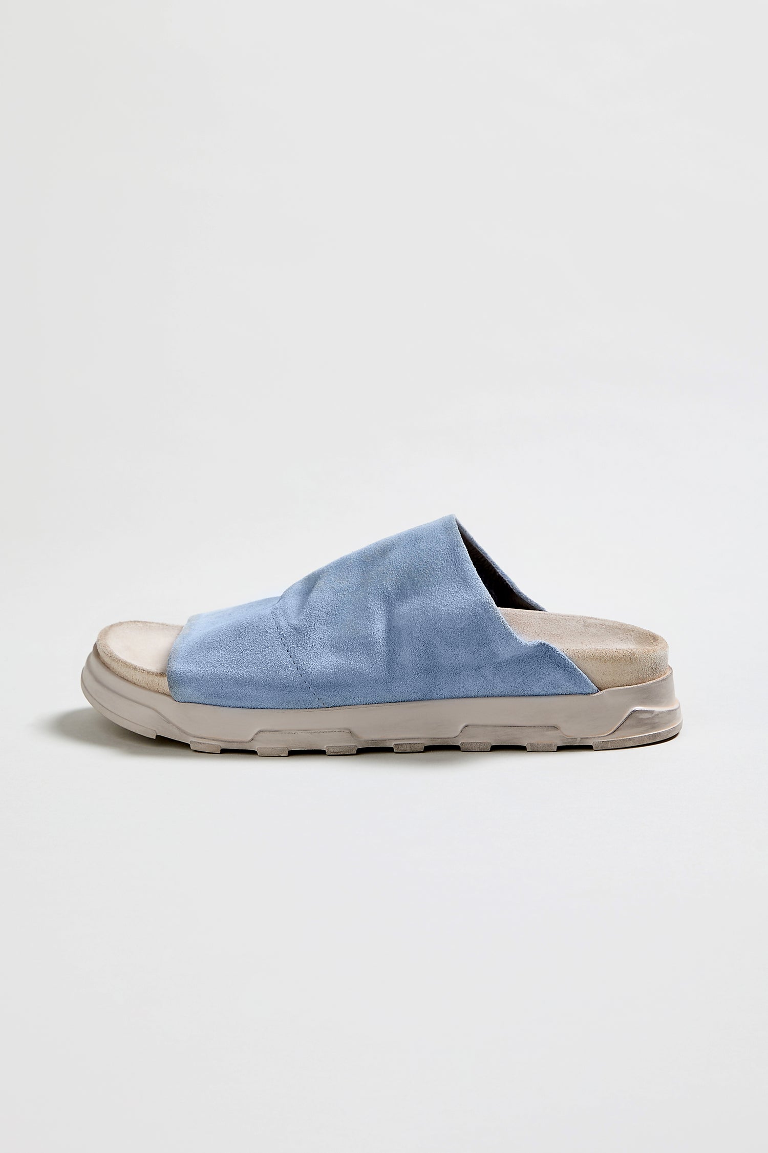 The Crushed Suede Sliders, style LOFI3364, feature a single light blue suede slide with an open toe and thick beige sole, displayed against a plain white background.
