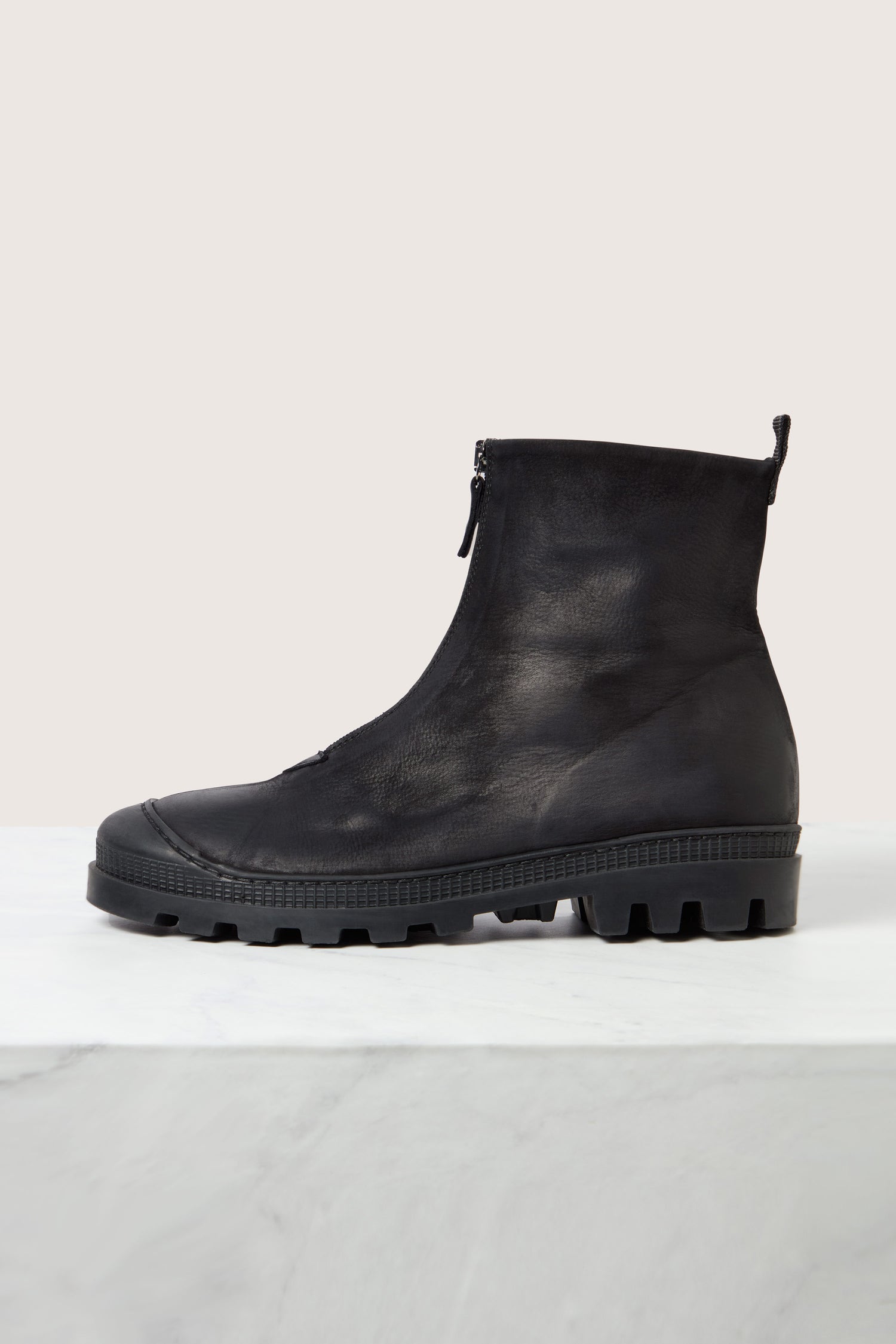 The Zip Front Leather Boots, featuring ankle-high luxurious black calfskin leather, a convenient side zipper, and a rugged rubber sole, are displayed against a plain background.